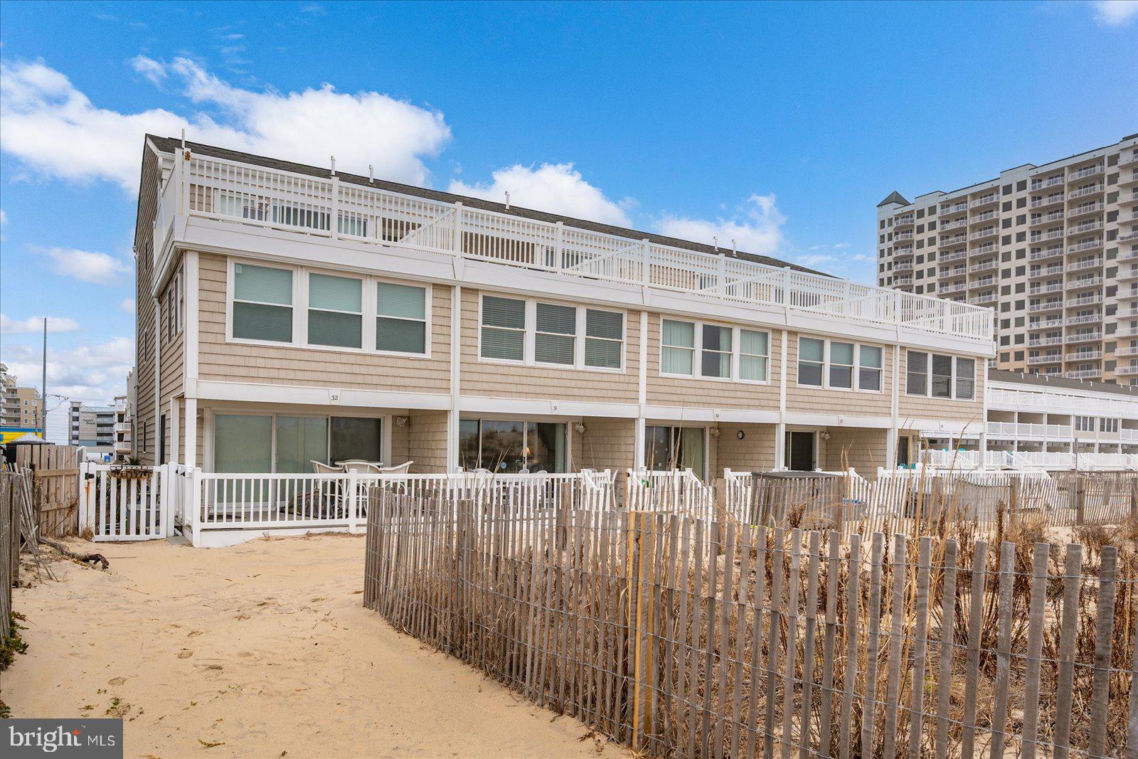 4607 Atlantic Ave., Unit 31 – Ocean Colony is a three-level direct oceanfront townhome offering sweeping, unobstructed views of the Atlantic Ocean in a prime midtown Ocean City location. Designed for both coastal living and strong rental potential, this residence features three spacious decks with maintenance-free composite decking, providing multiple outdoor living spaces to enjoy both sunrise and sunset skies. The ground/main entry level features the open-concept living, dining, and kitchen area, creating an inviting space for gathering and entertaining. The updated kitchen offers quartz countertops, a classic subway tile backsplash, breakfast bar seating, and a separate dining area. Sliding glass doors lead to a covered deck overlooking the dunes with a peek of the ocean—creating a naturally sheltered setting while keeping you just steps from the sand. The dune location provides added protection typical of oceanfront properties, and the sandy beach just beyond the deck offers a perfect place to relax and play in the sand. This level also includes a bedroom with French doors featuring a wall of windows that capture ocean views and fill the space with abundant natural light, along with a hall full bathroom. The second floor offers the largest bedroom, serving as the primary due to its generous size and featuring a wall of windows with ocean views and abundant natural light, along with a hall full bathroom and an additional bedroom with sliding doors leading to a spacious deck that captures beautiful sunset views. The top floor includes two additional bedroom areas and a full bathroom, along with an oversized deck showcasing direct oceanfront sunrise views and unobstructed vistas stretching both north and south along the coastline. With five bedrooms and three full bathrooms, this property comfortably accommodates large groups, making it an excellent investment property, vacation home, or year-round residence. Additional highlights include direct beach access from the unit, deeded beach rights, a community pool, and ample reserved community parking for residents and guests, plus additional street parking. The condominium association is well maintained and professionally managed, offering added peace of mind. Sold fully furnished for a seamless transition, this midtown oceanfront opportunity is just steps from shopping, dining, amusements, and nightlife—delivering the ultimate coastal lifestyle with outstanding income-producing potential.