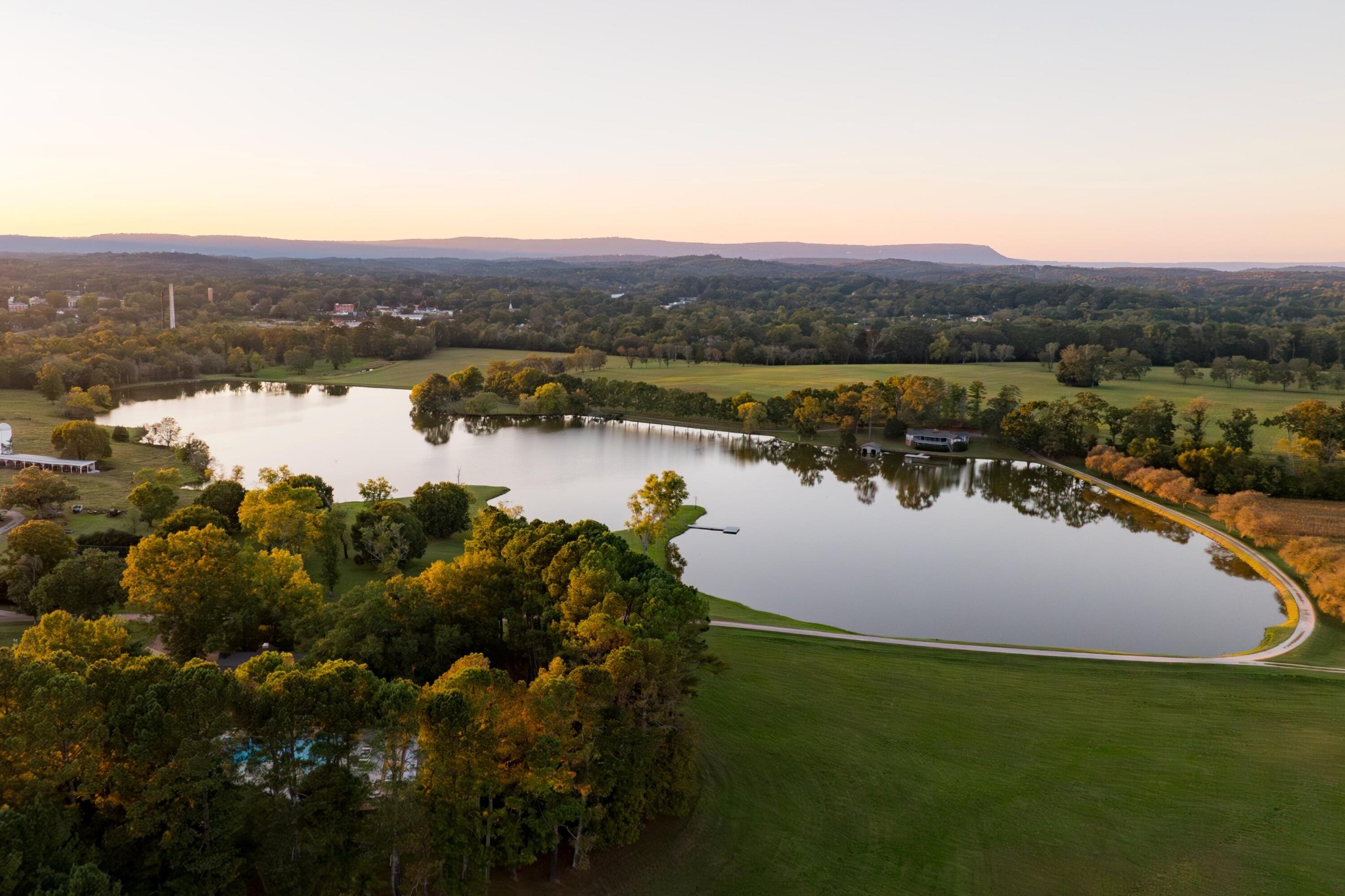 Gordon Lee Farm is a rare 305± acre legacy property set in the rolling landscape of Chickamauga, Georgia—an area known for its natural beauty, rich history, and strong sense of place. With a remarkable mix of large water features, fertile ground, and classic improvements, the farm feels both park-like and deeply rooted in the character of northwest Georgia. Portions of the property lie within the city limits of Chickamauga, yet the setting remains peaceful and private, offering the best of small-town charm and rural retreat. Owned by a family since 1939, Gordon Lee Farm is a place that brings people together having fostered countless celebrations, respite, communion, recreation, and memories.At the heart of the property is the 28± acre spring-fed Krystal Lake offering outstanding fishing and a tranquil setting. The 3,584± sq. ft. Lodge serves as the central gathering place well-suited for entertaining, featuring a large open floor plan with pass-through kitchen, 4 bedrooms, screened porch, pool, and shaded patios that extend the living space into the outdoors. The 2,174± sq. ft. Lake House overlooks the water, complete with four bedrooms, a dock, and covered boathouse. Nearby, additional improvements include a horse barn and riding ring, Manager's House, Stone House, and multiple barns to support farming and equipment needs.The land itself is equally exceptional. Gordon Lee Farm offers 1.5± miles along the significant Crawfish Spring that merges with nearly a mile of frontage along West Chickamauga Creek —creating an impressive network of water that encompasses nearly all of the property's boundary. The 45± acres of productive crop fields and the 140± acres of hayfields and pastures support the agricultural and recreational components of the farm. Classic white three-board fencing frames over a mile of road frontage.Equitable Ownership Interest. Contact listing agent for details.