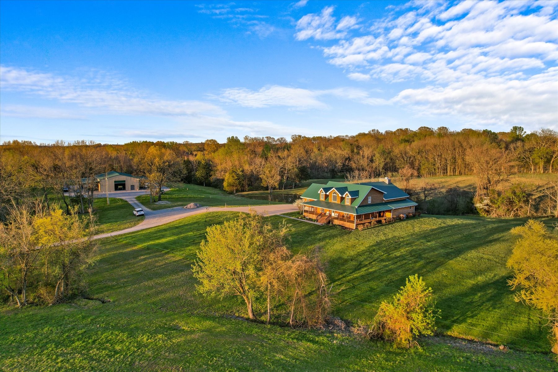 For the discerning buyer who refuses to choose between a life of absolute privacy and the pulse of one of America's most vibrant cities, this nearly 24-acre equestrian estate answers that call with rare eloquence.  Tucked deep into the rolling Tennessee countryside, this property offers a seclusion that feels genuinely earned, where the only sounds are the rustle of wind through the hills and the quiet rhythm of country living.  Just under 20 minutes to BNA Airport and 35 minutes away from the energy of downtown Nashville.The handcrafted log home is a study in warmth and intention, where rustic woodwork and timeless architectural detail meet the comforts of modern living across three spacious bedrooms and three well-appointed baths.  The wraparound porch invites you to exhale, offering sweeping views of the rolling landscape that stretch as far as the eye can follow, while the covered back deck frames a serene private pond that mirrors the golden light of both sunrise and sunset with equal grace.The equestrian possibilities here are genuine and ready to be shaped.  A modern storage barn stands primed for conversion into stables, a workshop, or whatever vision your lifestyle demands, and the expansive acreage provides the kind of space where horses move freely and freely breathe.  This is a property that understands the relationship between horse and land, between owner and horizon.What makes this estate truly rare is not any single feature, but the convergence of all of them.  Privacy this deep, proximity this convenient and an equestrian canvas this expansive rarely occupy the same deed.  For the buyer whose life demands both the sanctuary and the runway, this is not a compromise. This is the answer.