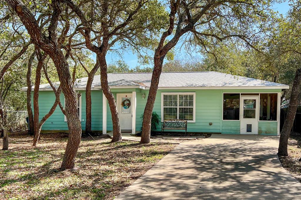 Nestled beneath large shade oak trees, this fully furnished beach cottage is the perfect coastal retreat! A welcoming side screened porch invites you to relax before stepping inside to a playful, light-filled interior with fun coastal charm. The semi-open living space flows into the kitchen, where a window over the sink is perfect for daydreaming. Double doors open to a covered back patio, overlooking a spacious, fully fenced backyard—ideal for gardening, entertaining, or even adding a pool and a storage shed for convenience. The driveway has ample room to park your boat and toys for your next bay adventures. Just a few blocks from the Rockport Arts District, Aransas Bay, and the beach, it's time to get your golf cart ready and enjoy the best of coastal living!