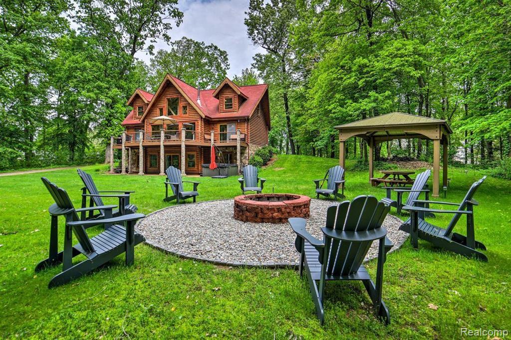 Tucked away on nearly an acre of secluded land, this stunning 5-bedroom, 3.5-bath log home offers 3,360 finished square feet of rustic charm and modern upgrades. Located just 25 minutes from Ann Arbor and 10 minutes from Jackson, this home captures the essence of a private “up north” retreat while still being close to everything. The main floor welcomes you with a spacious open-concept kitchen featuring granite countertops, ample cabinetry, and a generous island—perfect for cooking together or gathering with friends and family. The main-floor master suite includes private deck access, while the expansive great room boasts vaulted ceilings, walls of windows, and an electric fireplace with a wood stove hookup—ideal for entertaining in any season. Upstairs you’ll find two more bedrooms, a full bath, and a versatile loft area perfect for a library or playroom. The finished basement adds even more living space, complete with a large rec room, full bath, office/craft room, and two more bedrooms. Enjoy serene mornings on the full-length covered porch or evenings around the fire pit. Additional highlights include a private sauna, outdoor hot tub, dedicated game room, and newer HVAC and water heater. Just 0.2 miles from Gilletts Lake, this property offers the perfect balance of natural beauty, functional space, and modern comfort—truly a must-see. Property has been used as a Vacation rental and can be sold with a book of business, including almost fully booked summer season, great reviews, and fully furnished (at additional charge). Great Opportunity!