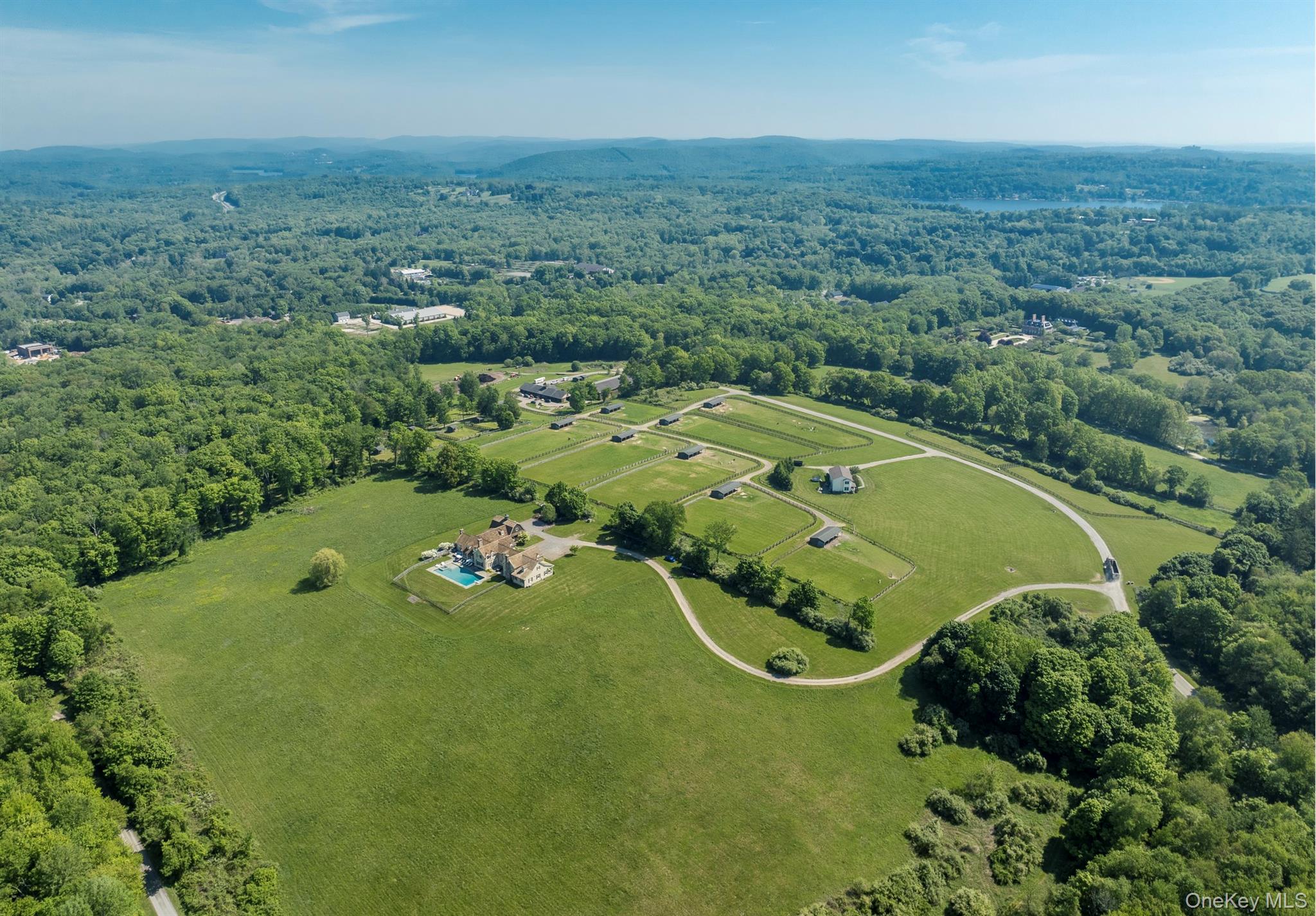 Red Horse Farm. An unparalleled opportunity to acquire 102 private acres in the heart of North Salem Equestrian Country. The approach is nothing short of captivating - with a winding driveway enveloped by lush greenery, rolling fields, classic stone walls, 360 degree panoramic views, and a sense of profound peacefulness. The spectacular 9,500 sq ft main residence exudes understated luxury - at its finest. Walls of French doors throughout the home blur the line between exquisite interior spaces and outdoor beauty. Upon entry, you are graced by an elegant, airy foyer with soaring ceilings, a stunning mahogany staircase, and striking molding and paneling throughout. The sensibility is one of old world charm & extraordinary quality, with a modern understanding of living and incredible room scale. The main floor includes a light filled living room with fireplace, formal dining room, a cozy paneled library with fireplace, family room with fireplace, butler’s pantry, wet bar, and a state-of-the-art chef’s kitchen with two inch thick marble countertops, viking appliances, and custom fixtures and cabinetry. French doors lead from the kitchen to a large screened-in porch with a massive stone fireplace, all positioned to survey the breathtaking views beyond while overlooking the enormous 30’ x 65’ Gunite pool & spa, with expansive terrace and entertaining area. Also on the main floor, there are two powder rooms, a light-filled mud room/ potting room with side entrance, wide back staircase, access to the three car garage and a well-designed laundry room. Located in its own wing on the main level through a private entry hall, the marvelous first floor primary bedroom suite offers a true refuge with outstanding his and hers bathrooms and closets, as well as french doors to a private seating area. Upstairs, there are two en-suite guest bedrooms, as well as two family bedrooms with a sitting area and full bath. There is also expansive attic space, additional storage rooms, and a lower level basement with 12 ft ceilings for endless possibilities of additional expansion. This remarkable property has served as a thriving alpaca farm for the past decade, with several Equestrian structures and possibilities still in place. Presently, there is a King Construction built 14 stall main barn with two wash stalls, two powder rooms, an office, a tack room, multiple outdoor shedrow barns, 17 grass turnout paddocks, a 180’ x 72’ Indoor Arena, a 135’ x 300’ site for an outdoor arena, two 1 bedroom, 1 bath grooms’ apartments, a commercial size 6 bay storage garage, plus a 3 bedroom, 2.5 bath Caretaker's residence. The property has coveted direct North Salem Bridle Trails access, abuts Olympic caliber stables and significant estates on all sides, and is located 1.7 miles from Old Salem Farm and within close proximity to other top area horse shows. Minutes to highways and the train, one hour from NYC. A rare and unreplicable offering.