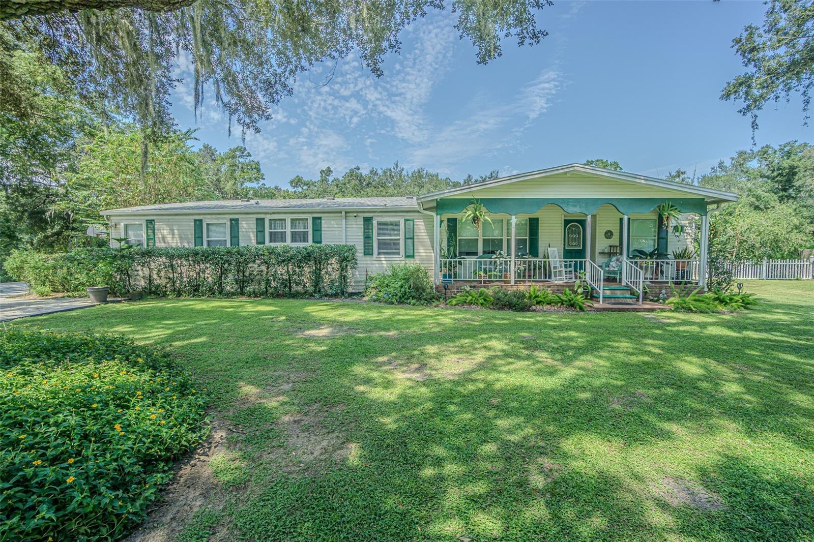 CLASSIC Brick and Wrought Iron Entry Welcomes you to this beautifully maintained and thoughtfully updated 4-bedroom (PLUS Office/Den), 3-bath home offering 2,008 square feet of comfortable living space on a fenced 1.11 acre lot in a serene, park-like setting. From the moment you arrive, the charm is undeniable... beginning with a rocking chair front porch overlooking front landscape and a leaded glass front door that sets a warm and welcoming tone.  Step inside to a light, bright, and open floorplan featuring luxury vinyl plank flooring throughout (2021) and a spacious split-bedroom layout that offers both functionality and privacy.  The expansive gathering room IS OPEN and connects to the kitchen, making it ideal for entertaining family and friends!  The kitchen boasts a large center island, updated Stainless steel appliances, white and gray two tone cabinets, undermount sink and eat in dining space.  A cozy wood-burning fireplace anchors the living room, creating a perfect spot for relaxing evenings.  The primary suite is a true retreat, offering an enormous walk-in closet, a private vanity space large enough to serve as a home office or nursery plus a beautifully updated ensuite with ceramic tile.  The second Bath features a skylight, filling the space with natural light.  REST EASY and Enjoy the outdoors year-round with a 12' x 18' screened back porch overlooking your private, fenced backyard, complete with a firepit area plus a 24' round above-ground pool with wooden sundeck—ideal for summer fun.  Additional highlights include a huge detached 24’ x 24’ garage with cathedral ceilings, dual garage doors, and a finished interior... perfect for a workshop or hobby space.  You’ll also appreciate the arbor leading from the driveway to your private retreat, large storage shed, 2021 Craftsman 30-gallon water heater with a 4-ton, 14 SEER Tempstar HVAC system installed in 2022.  A new dimensional shingle roof was added in November 2024, offering efficient utility bills and peace of mind for years to come.  This property has NO CDD fees, NO HOA fees and is on well and septic, offering lower utility costs which provides the perfect blend of peaceful country living, city close, with modern updates.  With its Light, bright, SPACIOUS floorplan boasting flexible spaces and inviting outdoor features, this home truly has it ALL!  Located on a quiet lane in Zephyrhills, with major highways nearby for easy access to Lakeland, Wesley Chapel, Tampa, shopping, restaurants, medical facilities, airports and Florida beaches!  CALL TODAY!