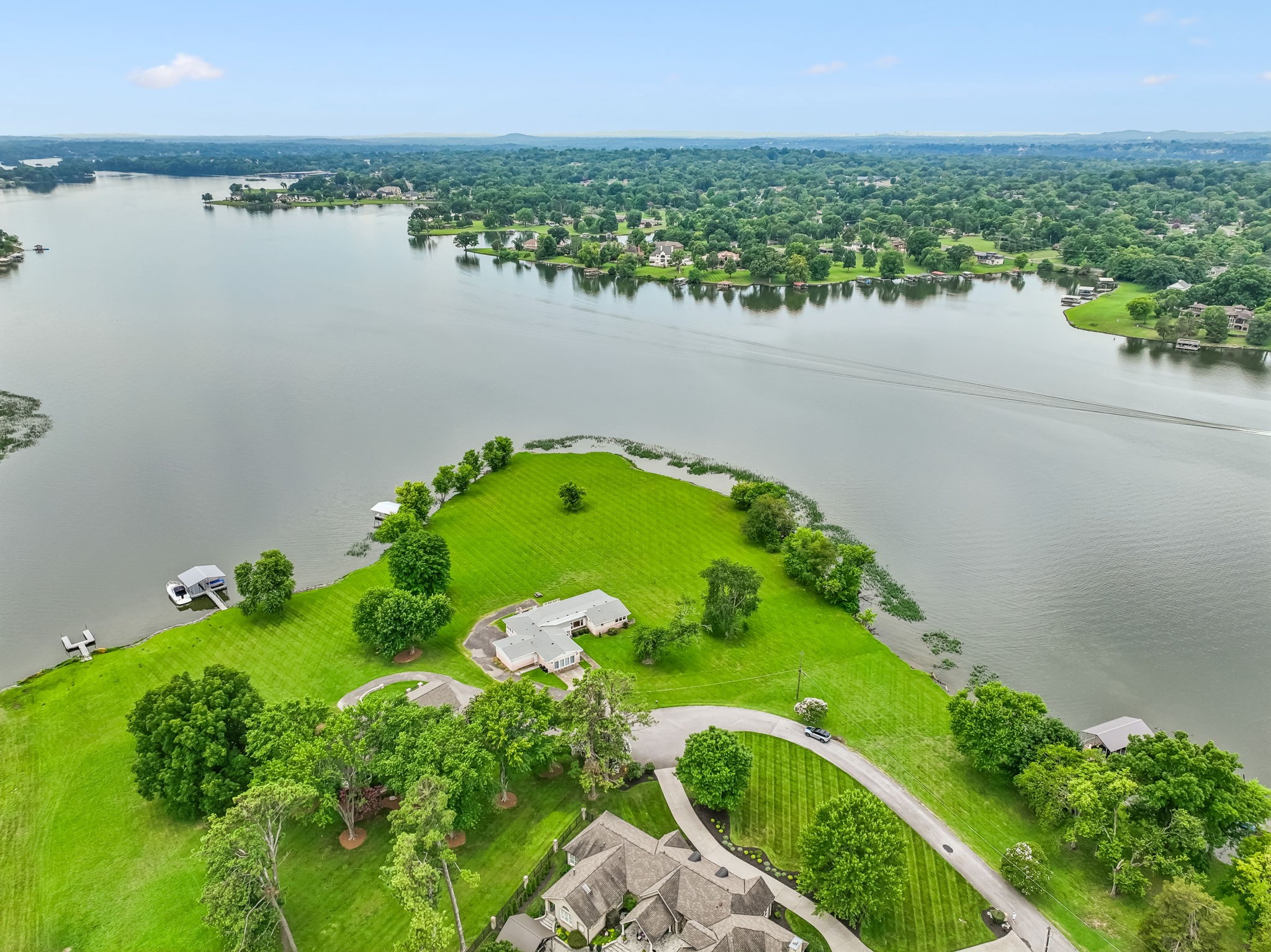 Don't miss out on this premier lot available on Old Hickory Lake.  The estimated 550' of shoreline and large adjoining Corps of Engineers property helps create a beautiful, park-like setting. The wrap-around views provide the perfect vantage point to enjoy lake life and watch boats pass by throughout the day. The property features a covered boat dock with a lift, situated in ideal water depth for easy lake access. Public sewer is available, but the current home has a septic system located in the front yard. The expansive back yard is suitable for your lagoon pool. For added convenience, a marina for fueling is located directly across the lake, and Moby Dick​ies restaurant is only five minutes away. The existing home was renovated a few years ago and serves as an excellent residence while you design your dream home. Check out the video of the panoramic views on the Links section. PLEASE DO NOT ENTER THE PROPERTY WITHOUT AN APPT WITH ME OR ANOTHER REALTOR.