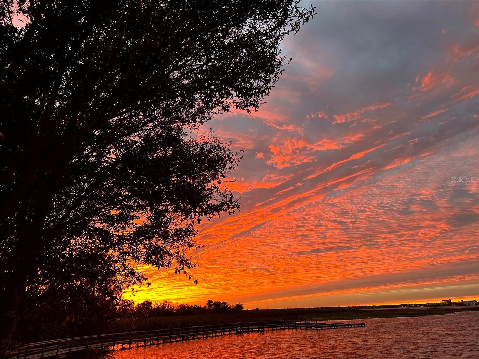 Moving to Florida? Experience breathtaking Florida LAKEFRONT SUNSETS from this custom home in the exclusive gated community of Sunset Pointe. Situated near shopping, DISNEY/UNIVERSAL/SEA WORLD, major transportation, hospitals, LAKE NONA, and NEO CITY and nestled amongst only 14 properties, this secluded oasis offers the perfect blend of privacy, security and convenience. On the shores of West Lake Tohopekaliga, the home is adjacent to a conservation area and is connected by a walking/biking path to historic Downtown Kissimmee, where you can catch a SunRail train to downtown Orlando/Winter Park, launch a boat from the marina, take in entertainment at the lakefront park, indulge in local dining, enjoy the nightly fireworks on the horizon from the attractions, celebrate the 4th of July with a spectacular view of the City fireworks, or catch the SpaceX launches from the front yard. The ORLANDO INT'L AIRPORT is just 16 miles away, and COCOA BEACH is a 60-mile drive. The low maintenance exterior of the home boasts a barrel tile concrete roof and genuine Tennessee fieldstone, which carries through to the waterfalls in the lagoon-style saltwater pool and hot tub overlooking the lake. The primary suite features dual walk-in closets and vanities, a deep jetted tub, shower with dual heads/slide bars/seat, and direct access to the lanai. The updated kitchen boasts upgraded appliances with double oven and microwave, cast iron Kohler sink, prep island, instant hot water dispenser, wine rack, pull-out trays, tilt-out trays and granite countertops. The spacious utility room has a laundry tub, built-in cabinetry w/desk, solid surface countertops, a washer/two dryers, built-in ironing board and built-in laundry hampers. Additional highlights include spacious 12' ceilings throughout, transom windows, bay windows, crown molding, architectural trim with tray/coffered ceilings, a gas ventless fireplace, 3 bookcases, custom louvered shutters and abundant storage. The home boasts a 3-zone energy-efficient A/C system and 80-gallon hot water heater with recirculating pump, water filtration system with ozonator, carbon filter and softener-no expensive water bills!  The garage measures over 1500 sf with 3 oversized doors (10x10 and 12x13), 12' and 14' ceilings, and a deep center bay for an RV/boat/antique car. It's also wired for EV charging and offers ample storage space, including abundant shelving, two huge closets, a utility sink/cabinet above and attic storage. Room for all your tools and toys!! Indulge in the ultimate entertainment experience with surround sound prewiring in the family room and primary bedroom, speaker prewiring on the lanai, intercom system and in-wall/ceiling speakers with volume controls throughout the home. Smart wire and dimmer switches, Google Nest(R) doorbell, LED lighting and automatic night lights provide some of the latest technology and conveniences. If you enjoy spending your leisure time fishing, boating, bird/nature-watching, playing pickle ball or simply relaxing by the lagoon-style saltwater pool with fountain and waterfalls, you won't want to miss the opportunity to own this custom home of unparalleled quality and luxury. No expensive CDD fees and not in a flood zone!