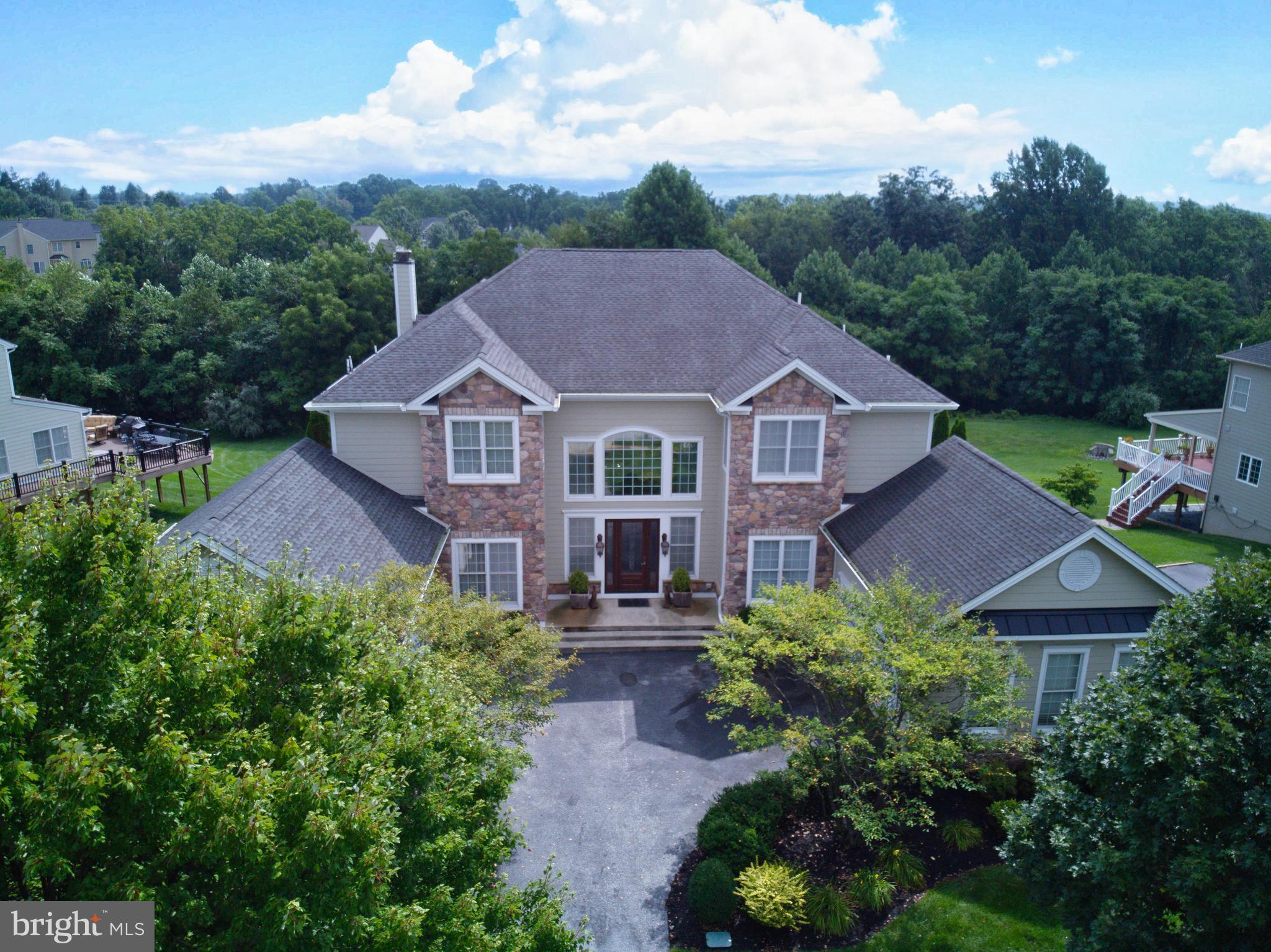 Welcome to Stonington Drive—a truly one-of-a-kind luxury residence where every room has been thoughtfully reimagined to blend timeless elegance, exceptional craftsmanship, and effortless entertaining.Step through the impressive entry door with frosted glazing into a breathtaking two-story foyer, highlighted by a grand twin curved staircase, extensive crown molding, designer accent lighting, and a stunning crystal chandelier that immediately sets the tone for the home.Conveniently located on the main level is a private guest suite, offering plush carpeting, oversized windows with custom window treatments, ceiling fan with light, custom-organized closet, and a beautifully appointed ensuite bath featuring an elegant tiled walk-in shower.The spectacular two-story dining room is designed to impress, with a soaring wall of windows overlooking the incredible outdoor living space and fireplace. This expansive room comfortably accommodates large gatherings while showcasing wide-plank engineered hardwood flooring and an elegant statement chandelier.The gourmet kitchen is a chef's dream, thoughtfully designed with every luxury in mind. A spacious center island with seating for three anchors the space, complemented by quartz countertops, a designer tile backsplash, custom illuminated shaker cabinetry, and premium Wolf appliances, including a six-burner range with oven, wall oven, and microwave/convection oven. Wine and beverage refrigerators, a coffered ceiling with recessed lighting, and a bright casual dining area complete this exceptional culinary space.Flowing seamlessly from the kitchen, the great room continues the coffered ceiling detail and offers expansive windows overlooking the wraparound deck, a striking floor-to-ceiling stone wood-burning fireplace, custom built-in cabinetry, and wide-plank engineered hardwood flooring—creating a warm yet sophisticated gathering space.The formal living room is equally remarkable and was even slated to be featured in a design magazine. Beautiful architectural details, refined finishes, and exceptional craftsmanship make this an unforgettable space for entertaining and relaxing.Upstairs, an elegant balcony overlooks both the grand foyer and dramatic dining room, enhancing the home's open and airy design.Occupying the private north wing, the luxurious owner's suite is a true retreat. Enter through solid double doors into a gracious sitting room accented by detailed crown molding and decorative columns. The spacious bedroom features custom built-in bookcases with an integrated media center, plush carpeting, and motorized custom window treatments.The spa-inspired owner's bath rivals those found in the world's finest luxury hotels. Double French doors lead to dual custom walk-in closets and a dedicated dressing and makeup room complete with triple mirrors, marble countertops, and custom cabinetry. The spectacular bath also features a glass-enclosed multi-head shower, a freestanding slipper soaking tub surrounded by elegant wainscoting, dual vanities with dedicated grooming stations, and a custom illuminated linen cabinet that completes this exceptional space.The south wing offers three additional generously sized bedrooms, each thoughtfully designed with custom finishes and neutral décor. One bedroom features its own private ensuite bath, while the remaining two share a beautifully appointed Jack-and-Jill bathroom. All bedrooms include custom window treatments and ceiling fans for comfort and style.The outdoor living spaces are nothing short of extraordinary, creating the atmosphere of a five-star private resort. A stunning wraparound deck overlooks the spectacular pool and lounge areas, while a covered outdoor living room features a stone fireplace, outdoor television, and generous seating with auxiliary heating for those cool fall evenings. Multiple dining and grilling areas provide the perfect setting for everything from intimate evenings to large-scale entertaining.