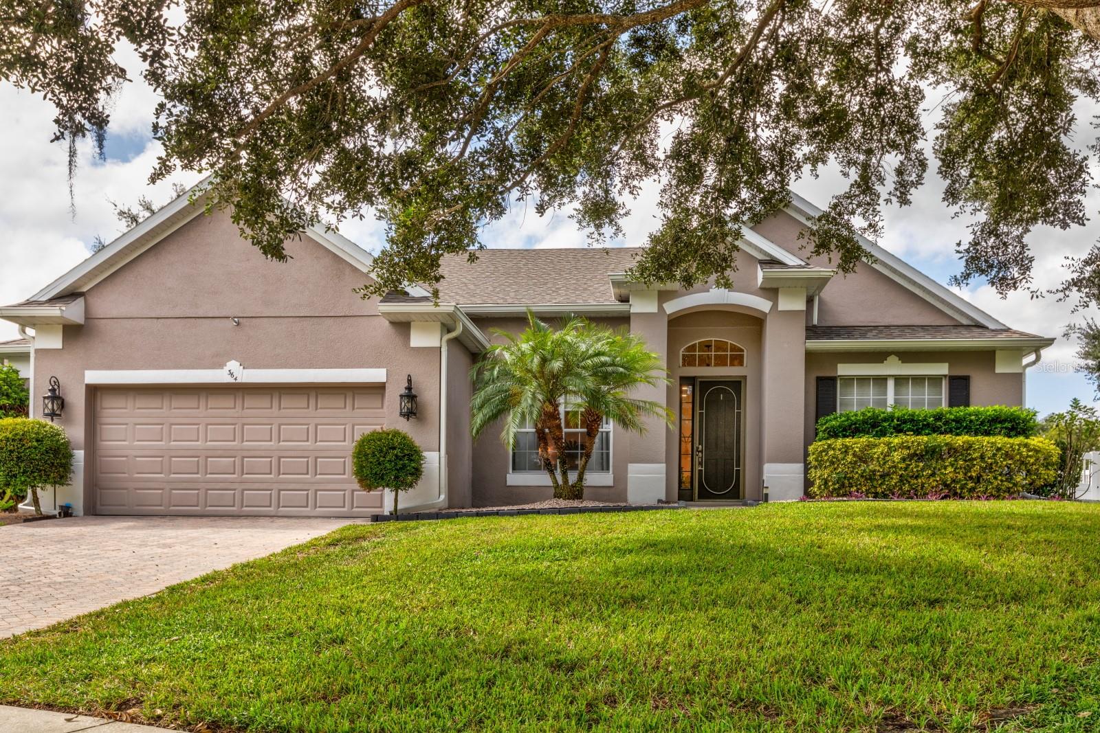 Beautifully maintained Eustis home situated on a quiet corner lot in the gated community of Blue Lake Estates. This inviting, family-friendly residence offers peaceful surroundings with subtle lake views while being conveniently located just minutes from shopping, dining, hospitals, top-rated schools, and the charming neighboring city of Mount Dora. The welcoming entry showcases cherrywood flooring and opens to a thoughtfully designed floor plan ideal for both everyday living and entertaining. A private office or study with an adjacent full bath provides flexibility for remote work, guests, or multigenerational living. A formal dining room offers the perfect setting for family meals, holidays, and special occasions. The open-concept living area features soaring 12-foot ceilings throughout, creating a bright and airy atmosphere. This central gathering space flows seamlessly into the kitchen and outdoor living areas, making it easy for family and guests to stay connected. Large windows bring in abundant natural light and enhance the home’s warm, welcoming feel. The kitchen is designed with functionality and connection in mind, featuring a center island, breakfast bar, eat-in nook, custom pantry, and ample cabinetry and counter space. Whether preparing daily meals or hosting gatherings, the open layout allows for effortless interaction with the living area and backyard. Sliding doors extend the living space to an expanded covered porch, ideal for outdoor dining or relaxing year-round. The fully fenced, landscaped backyard and side yard provide a private and secure space for children to play, pets to roam, and families to enjoy outdoor activities and entertaining. The spacious primary suite serves as a peaceful retreat, offering room for large furnishings and a luxurious en-suite bath with dual vanities, a soaking tub, a separate shower, and two generous walk-in closets. The split-bedroom floor plan provides privacy for the entire household, with two additional bedrooms, a shared bath, and a versatile flex space perfect for a playroom, home gym, study area, or additional bedroom. Storage is abundant throughout the home, including generous closet and linen space, a custom pantry, and a two-car garage with a fan and convenient bump-out—ideal for bikes, sports equipment, a workshop, and an extra refrigerator. A fully floored attic offers exceptional additional storage for seasonal items or long-term needs. This home has been immaculately maintained and thoughtfully updated, providing peace of mind for years to come. Major improvements include a new roof (September 2021), HVAC replacement (May 2019), and a newer hot water heater. Additional upgrades include interior and exterior paint, plantation shutters, a digital networking center, 21 new can lights, and numerous other enhancements. Blue Lake Estates is a gated community known for its quiet streets, well-kept surroundings, and welcoming atmosphere. Residents enjoy a sense of security and community. Priced below market value, this move-in-ready home offers outstanding space, comfort, and location for today’s families. Schedule your private showing today and experience all this exceptional property has to offer.