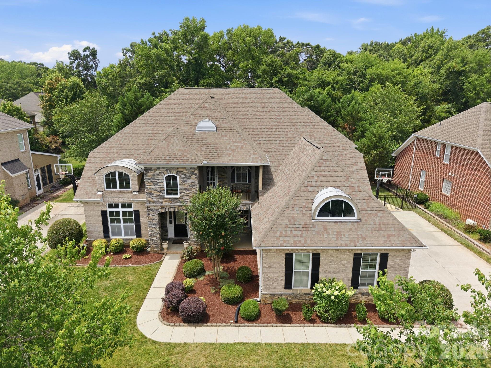 Stunning all-brick home featuring a desirable 3-car side-load garage, nestled on a beautifully landscaped, fenced homesite backing to a private natural area. Thoughtfully designed with neutral décor throughout, this move-in-ready home offers an exceptional blend of elegance, comfort, functionality, and privacy.The spacious main-level primary suite provides a private retreat, while the thoughtfully designed floor plan includes a formal dining room, family room, living room, and two dedicated office spaces—perfect for today's flexible lifestyle. The gourmet kitchen showcases freshly painted white cabinetry, granite countertops, double wall ovens, and ample space for entertaining and everyday living.Designed for convenience, the home features dual staircases, a generous loft ideal for family gatherings, and four additional bedrooms upstairs. Two bedrooms offer private en-suite baths, while the remaining two share a Jack-and-Jill bathroom, creating an ideal layout for families of all sizes.Step outside to enjoy the expansive covered porch complete with an outdoor kitchen and built-in grill, overlooking a serene, private backyard surrounded by mature landscaping and natural views—an ideal setting for relaxation and entertaining.Recent updates include gleaming Luxury Vinyl Plank (LVP), fresh interior paint, new carpeting, freshly painted cabinetry with updated hardware and a recently installed Tesla Wall Charger, providing convenient at-home EV charging.Ideally situated in one of Ballantyne's most sought-after locations, this home is within walking distance of Rea Farms and just minutes from Waverly, placing premier shopping, dining, fitness, and entertainment at your fingertips. With convenient access to I-485 and top-rated schools, this exceptional property offers a rare blend of privacy, convenience, and everyday luxury. Don't miss your opportunity to make it yours.