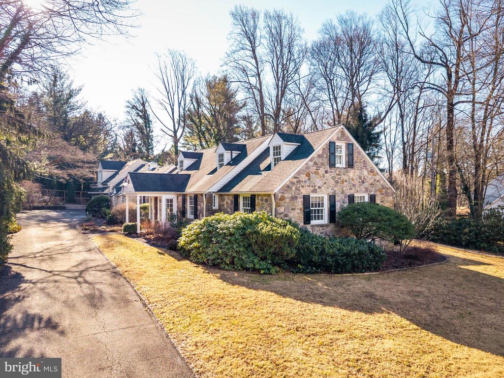 Quietly elegant and thoughtfully designed, this home is distinguished by its graceful proportions, natural flow, and inviting sense of warmth throughout. From the moment you enter, there is an immediate feeling of comfort and ease, with rooms that feel welcoming and well balanced, well suited to both everyday living and relaxed entertaining.The main living spaces are warm and inviting. The living room features a bay window, recessed lighting, and a gas fireplace, creating a comfortable focal point. A sunny dining room with French doors opens to a large flagstone patio with awning, extending the living space outdoors and making entertaining feel effortless. A comfortable den and a conveniently located powder room add versatility to the main level.The updated eat-in kitchen serves as the heart of the home, ideal for daily meals and gathering. Finished with granite countertops, a bar area, and wood flooring throughout the first floor, it offers a timeless aesthetic paired with practical design. Just off the kitchen is a back hall with an additional powder room and a dedicated laundry room. Radiant floor heating throughout the first floor enhances year-round comfort.A first-floor bedroom provides convenient accommodation for guests or use as a private office. Also on the first floor, the primary bedroom features a walk-in closet and a well-appointed bathroom with neutral finishes and granite countertops.Upstairs, two additional well-sized bedrooms with closets share a full hall bath, offering comfortable space for family or guests.The finished lower level provides additional living space, well suited for relaxing, entertaining, or recreation. It includes a full bathroom with a spa tub, along with a laundry area and storage.Beyond the main residence, the property includes a three-car garage with a two-bedroom apartment above, offering excellent additional space for guests or extended stays. A separate, dedicated golf studio provides a unique setting for recreation or personal pursuits while maintaining the home’s overall sense of balance.Set on beautifully landscaped grounds with a fenced yard and established gardens, the outdoor setting is both private and inviting. Notable improvements include new windows throughout, a renovated interior, and a newer HVAC system.This is a home defined by warmth, thoughtful design, and quiet elegance, appreciated immediately and over time.