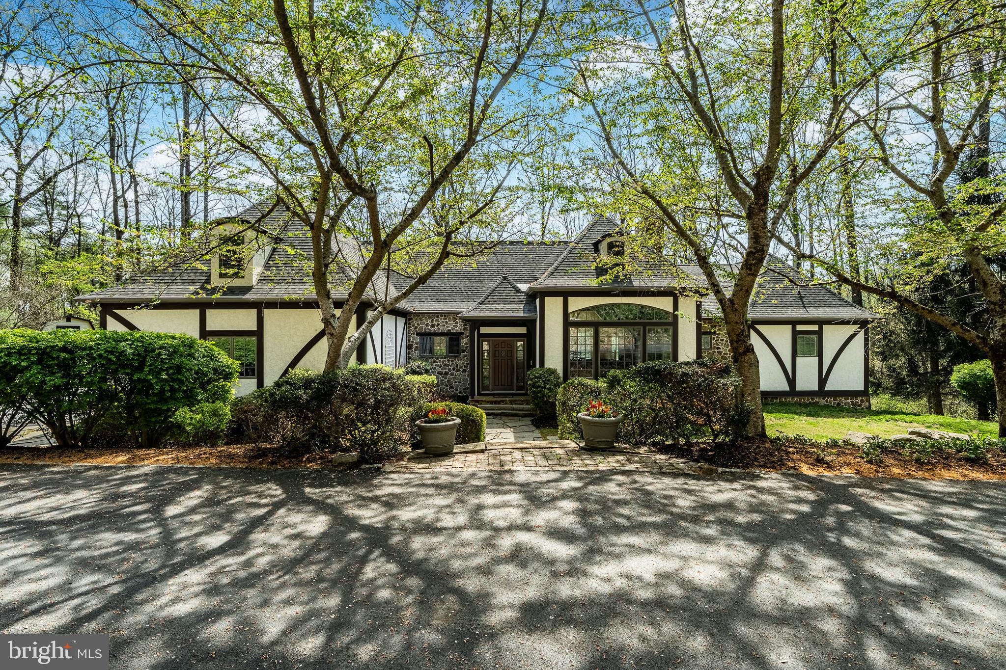 In one of the most sought after country property locations in Chester County, surrounded by protected open space in the French Creek Valley near Warwick Furnace, yet within easy reach of all amenities via the Route 23 and Route 100 corridors. This custom Entrekin-built luxury estate is one of the most distinguished properties currently offered in Chester County. Set on 12 secluded acres and surrounded by protected open space along French Creek, this 4-bedroom, 3 full, 2 half-bath English Manor residence with Tudor-style elements blends timeless style with superior craftsmanship. Boasting over 5,000 square feet of living space, the home features handcrafted woodwork, fine millwork, and elegant architectural details throughout.The majestic interior offers a sprawling open floor plan designed for both grand-scale entertaining and intimate living. Recent high-end updates include professionally refinished hardwood floors, new carpeting, a fresh designer paint palette, and fully updated bathrooms. The expansive Great Room (18’ x 40’) serves as the home’s heart, boasting lofted beamed ceilings and a fireplace flanked by custom built-ins. Bathed in southern light, this space flows into a chef’s kitchen featuring premium stainless appliances, including a new double oven and stovetop. Adjacent, the cozy family room offers a second floor-to-ceiling stone fireplace.A stone archway leads to a practical wing housing a freshly painted 3-car garage, laundry with exterior access, and a guest powder room. On the opposite wing, the main-level primary suite provides a private sanctuary with a lofted ceiling, south-facing deck access, and a spa-like bath with a whirlpool tub. The upper level features two bedrooms with a Jack & Jill bath.Practical elegance continues with significant infrastructure improvements for total peace of mind: a new roof and skylight, comprehensive HVAC replacement with a soft-start unit, a tankless hot water system, and a whole-house battery backup. Outside, the 12-acre sanctuary offers a repaved driveway, a new shed, and manicured landscaping.The walk-out lower level—complete with a wet bar, new wood-burning stove, full guest suite, and walls of windows—is ideal for an au-pair or multi-generational living. Outside, the entertaining continues on a sprawling patio anchored by a magnificent stone fireplace.Located in the sought-after Owen J. Roberts School District, this stately property is protected in perpetuity by a conservation easement held by the French and Pickering Creeks Conservation Trust. A home of this caliber—so rich in quality and meticulous updates—must be experienced in person to be truly appreciated.