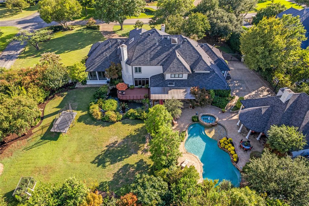 This extraordinary private estate spans 1.08 acres in one of Dallas’ most prestigious neighborhoods & is designed for outdoor living & entertaining at the highest level. The grounds showcase a park-like setting with a 4000-gallon koi pond with more than 50 fish, 2 waterfalls, & an observation deck, creating a serene focal point. With no neighbors on one side, the beautifully landscaped ppty ensures exceptional privacy. Multiple outdoor living areas invite year-round entertaining. The resort-style backyard features a pool & spa with pool bath, 2 pergolas, fireplace, full kitchen - 54” Wolf grill, sink, and fridge. A separate gated multi-purpose space offers endless possibilities, from a future pickleball court to dog area or recreational retreat. Professional landscape lighting, mature trees, and expansive lawns complete the setting. Inside, the transitional-style home blends timeless elegance with modern luxury. It offers 5 bedrooms, 6 baths, plus 400sf detached qtrs with bedroom, ensuite, and kitchenette. The chef’s kitchen is anchored by a spacious island, Sub-Zero refrigerator, Wolf 6-burner cooktop, Miele double ovens, steam oven, warming drawer, microwave-third oven, 48-bottle wine fridge, dual sinks, dual dishwashers, and custom cabinetry. A main wet bar with copper sink, ice maker, and decorative cabinetry complements the space, while a 200-bottle temp-controlled wine closet & dining room with courtyard fountain views elevate entertaining. The downstairs primary suite overlooks the backyard with a wall of windows & french doors. Additional spaces include a private office with a view of the koi pond, oversized den with wet bar & ensuite, hidden craft room, and media room with theater seating, wet bar, and half bath. Luxury finishes include 3 fireplaces, surround sound indoors & out, 4-car garage (2 and 2), motorized gated courtyard, security cameras & 30-day DVR system, and optional Royalwood Armored Patrol services add peace of mind to this fabulous estate.