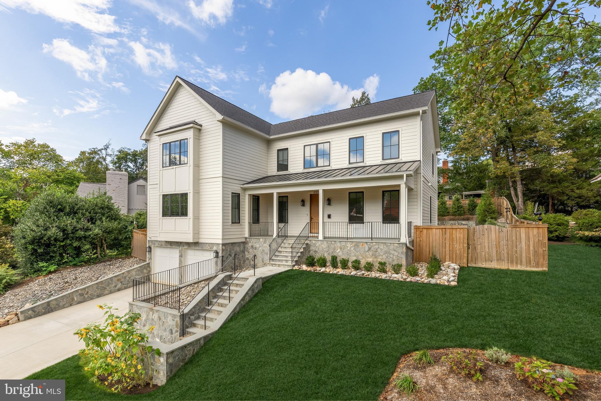Tucked away on a quiet cul de sac in coveted Country Club Hills, 4283 38th Street North offers a rare blend of seclusion, sophistication, and striking design. Elevated above the street and framed by manicured landscaping, this custom residence was built in 2023 by CR Custom Homes and showcases where East Coast tradition meets West Coast style.The exterior merges the charm of a modernized Colonial with warm farmhouse influences. Interiors, curated by Santa Monica designer Tracy Gilmore, embrace a refined Southern California aesthetic. A broad stone staircase framed by tiered retaining walls leads to a welcoming front porch, setting the stage for elegance inside.A dramatic foyer, filled with natural light, spans the main level and highlights exceptional craftsmanship: wide plank white oak floors in herringbone, ten foot ceilings, eight foot quadruple hinged doors, Phillip Jeffries wallpaper, and motorized window treatments.Off the entry, a private study balances a main level bedroom suite ideal for guests or multigenerational living. The formal dining room, introduced by a refined vestibule, features a large bay window and connects via a butler’s pantry to the kitchen.At the center of the home, the kitchen is both showpiece and gathering space. Carrara marble wraps perimeter counters and backsplash, while a black leathered marble island adds contrast. Stacked inset cabinetry conceals appliances for a clean, modern look. An adjacent dining area and spacious family room flow seamlessly, with reclaimed wood beams, a linear fireplace, and arched built ins enhancing the atmosphere.The primary suite occupies its own upper level wing. A vestibule introduces the serene bedroom, while a second leads to a boutique style dressing room with custom shelving. The spa inspired bath includes radiant heated floors, a walk in shower room, double vanity, and separate water closet.At the top of the stairs, a loft creates a cozy reading nook and connects to three additional ensuite bedrooms with custom walk ins. A bold laundry room with patterned tile completes the level. The lower level includes a fifth bedroom suite, a large recreation room, and a mudroom accessing the two car garage.The backyard is fully fenced and landscaped, with open lawn, hardscape, and mature greenery. A covered rear porch with retractable screens provides seamless indoor outdoor living for year round dining and relaxation.Modern systems elevate efficiency and comfort, including impact rated windows and doors, backup generator, tankless water heater, integrated Sonos, comprehensive security, and extensive drainage infrastructure.Located just a mile from Chain Bridge and moments from Glebe Road Park, the home offers easy access to city amenities and natural beauty alike.4283 38th Street North is more than a home. It is a masterclass in design, comfort, and function. Every finish has been thoughtfully selected. This is luxury living at its finest.
