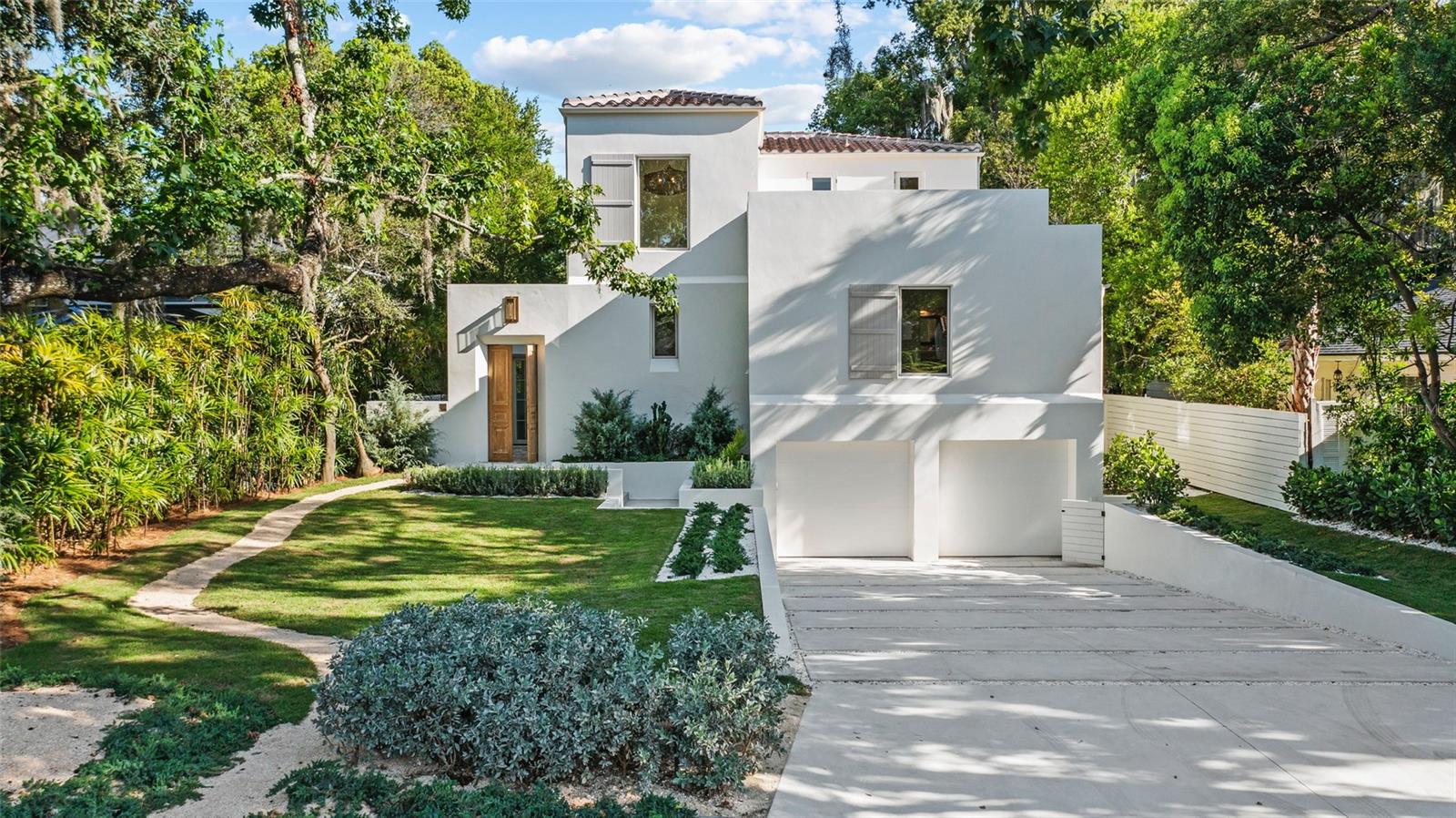 In the heart of Winter Park’s coveted Vias neighborhood, 1150 Via Salerno is a newly completed Mediterranean-minimalist residence that blends architectural refinement w/ organic warmth. Designed and developed by Steve and Jodie Warrick Konold of Scout & Co., the 3,850 sf layout offers 4 bedrooms & 5.5 baths, wrapped in the intentional privacy of a luxury retreat. Beyond its terraced walkway and garden courtyard—envisioned in collaboration w/ architect Cynde Norris—French antique gates open to a native-planted entry garden, creating a soft transition to the interior. A glass foyer introduces a tongue-and-groove ceiling & woven rattan chandelier, sourced & designed in London, leading to a sculptural stairwell that anchors the open floor plan. The great room features soaring ceilings, a sleek fireplace & walls of glass windows & doors that blur the boundary between inside & out. Ten-inch baseboards meet level 5 drywall in a clean reveal, paired w/ micro-crete flooring on the main level & wide-plank European oak upstairs. In the kitchen, materials w/ function are elevated w/ a Thermador dual-fuel range w/ six burners & griddle, custom plaster hood, full refrigerator & freezer columns & a large island topped in honed black quartzite. The surrounding cabinetry is crafted from hand-carved V-groove panels w/ soft-close hardware & integrated pullout storage. Caesarstone surfaces run along the perimeter while steel-and-glass open shelving w/ a sculptural black sconce balance the composition. A vintage chandelier from Prize Home & Garden sourced in Round Top completes the room w/ warmth & charm. The primary suite occupies a private wing on the main floor accessed via antique gallery doors that lead to the rear courtyard. Vaulted ceilings, a custom walk-in closet w/ a spa-like bath provide a luxurious retreat. Features include a long double vanity, matte black Kohler fixtures, a freestanding tub, plaster walk-in shower w/ built-in bench & separate water closet. On the mezzanine level, the powder bath makes a dramatic statement w/ a floating black quartzite trough sink w/ handwoven mirror. Across the hall, the laundry room blends beauty w/ utility w/ custom cabinetry, matching quartzite surfaces, matte black fixtures & a side-by-side front-load washer & dryer. A nearby guest suite is marked by an antique door entry. The en suite bath features a hand-painted tile threshold & suede-framed mirror. Two upstairs bedroom suites feature en suite baths, designer lighting, distinctive mirrors & continuous European oak flooring. Positioned at the front of the home, the rooftop terrace is accessible via the upper hallway & a guest suite. The detached casita opens to the pool courtyard through accordion glass doors and features micro-crete floors, a woven rattan chandelier, and a full bath—ideal as a studio, gym or office. Outdoor spaces include two garden courtyards, a fully fenced grassy backyard, a heated saltwater pool, and a rooftop terrace, all enclosed by masonry walls w/ a board-on-board privacy fence for quiet seclusion. Additional features include a lower-level two-car garage, storage closet, three HVAC systems, Rinnai tankless water heater, Sierra Pacific windows, customized closets throughout, solid core interior doors, 6” round gutters & a Barcelona barrel tile roof in Espresso Blend. Thoughtfully designed & beautifully executed, 1150 Via Salerno offers a refined lifestyle tucked within one of Winter Park’s most exclusive enclaves.
