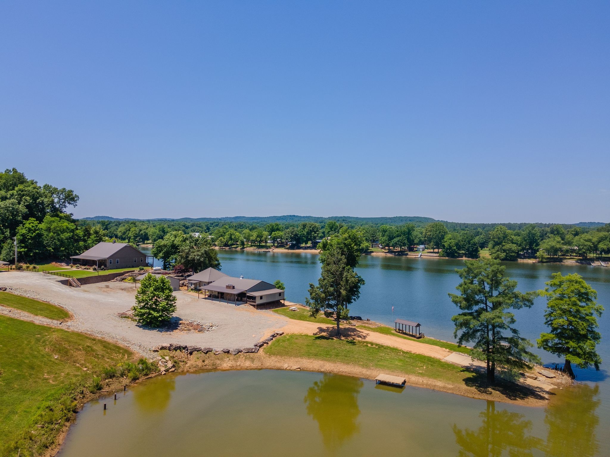 Price drastically reduced by $400,000..  Private 88 +/-acre waterfront retreat on the Tennessee River. Main Waterfront Home features 2 bedrooms, stunning woodwork, galley style kitchen, along with a striking two-sided fireplace. Two large covered porches add even more enhancement while offering views of whitetail deer from the front porch, and relaxing waterfront views off the back. High-speed internet is also available. The Guest Home has an open floor design and beautiful woodwork as well. The Large Pavilion has approximately 3,300 SQFT under the roof, a bath, a refrigerator, and a stone pizza oven/grill/fireplace all in one! Very own boat ramp and dock that's located inside an inlet just off the river, offering protection from the current and wake from other boats. This inlet could possibly be expanded into a marina. Numerous building sites make this property perfect for development. Also has Marketable Timber