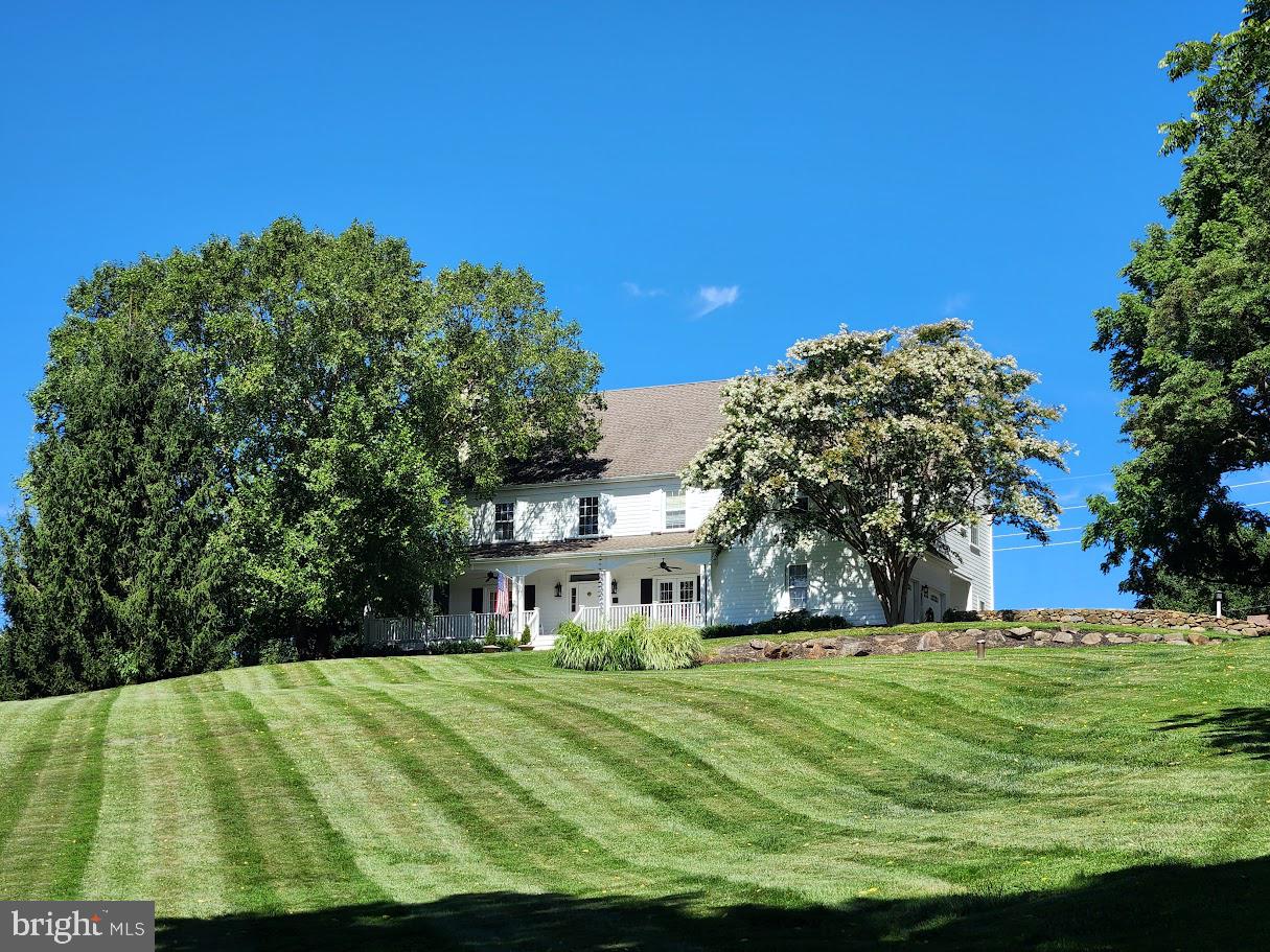 Welcome to 1051 Saint Matthews Road, a prestigious Chester Springs Oasis set on 2.67 private acres. A long, gently sloping front lawn leads to the stately southern-facing home, where a wide wraparound porch with ceiling fans offers panoramic views. Step through the front door into a dramatic two-story foyer, where natural light pours in and sets the tone for the elegant yet comfortable interior. To your left, the living room features a propane fireplace, crown molding, and recessed lighting, along with French doors that open directly onto the front porch—ideal for seamless indoor-outdoor living. To your right, the formal dining room is enhanced with timeless wainscoting and floating crown molding, along with another set of French doors to the porch, perfect for hosting guests in style. Throughout the main level, refinished hardwood floors and thoughtful design details create an open, airy feel. Sliding barn doors add both character and function, subtly separating spaces while allowing light to flow freely. The newly renovated gourmet kitchen is a chef's dream, featuring brand-new appliances (including double wall ovens with convection, a dishwasher, and a refrigerator), quartzite countertops and backsplash, a central island with an induction cooktop and pop-up vent, marble inlay accent flooring, recessed lighting, and a side door to the backyard patio. A sunny breakfast room just off the kitchen offers additional casual dining space, complete with crown molding and hardwood floors. Adjacent to the kitchen, a spacious family room with a second propane fireplace, ceiling fan, and hardwood floors provides more room to gather. A powder room rounds out the space with wainscoting, crown molding, and an antique English wash stand. The open-concept layout makes entertaining easy, and newly installed Andersen double doors connect the kitchen and living space to the expansive slate patio—extended in 2024 to create the ultimate outdoor entertaining area. Upstairs, new hardwood floors run through the hallway into a primary suite with a tray ceiling, a ceiling fan, walk-in closets, and a stunning spa-like bathroom. Setting the scene to unwind, the primary bath includes a jetted, deep soaking tub perfectly positioned beneath a new picture window overlooking the lush, tree-lined backyard, along with a walk-in shower and a double vanity. Three additional bedrooms are sizable with durable, elegant vinyl flooring and share two thoughtfully updated baths - One with a standing shower, the other with a tub. One of these bedrooms offers a private-style bath, while another includes a ceiling fan and pull-down attic access. An additional bedroom or home office is located just off the primary suite, featuring built-in shelving, offering flexible living options. Not to be missed, the convenience of second floor laundry with marble flooring and an All-In-One Washer/Dryer. The fully finished walk-up lower level offers full lower-level living space, featuring a flex space perfect for work or guests alike, a generous half bath, an exercise room, and an all-purpose entertaining area complete with a custom bar. The home includes a private well and septic system. Outdoors, the beautifully landscaped grounds are filled with blooming hydrangeas, peonies, red pear and peach trees, and a beautiful balance of open lawn and natural privacy. In winter, enjoy peaceful views through the trees down to a tranquil pond beyond the property line—a stunning reminder of the natural beauty that defines Chester Springs. This home has been meticulously maintained and updated and is ready for your family. With dual-zone HVAC you will enjoy comfortable surroundings year-round! Local to the PA turnpike, Marsh Creek Park, and the shops and dining in Exton while still tucked away, this home offers the perfect combination of accessibility and privacy. Thoughtfully designed and masterfully built with 2x6 construction, this residence is truly a one-of-a-kind property!
