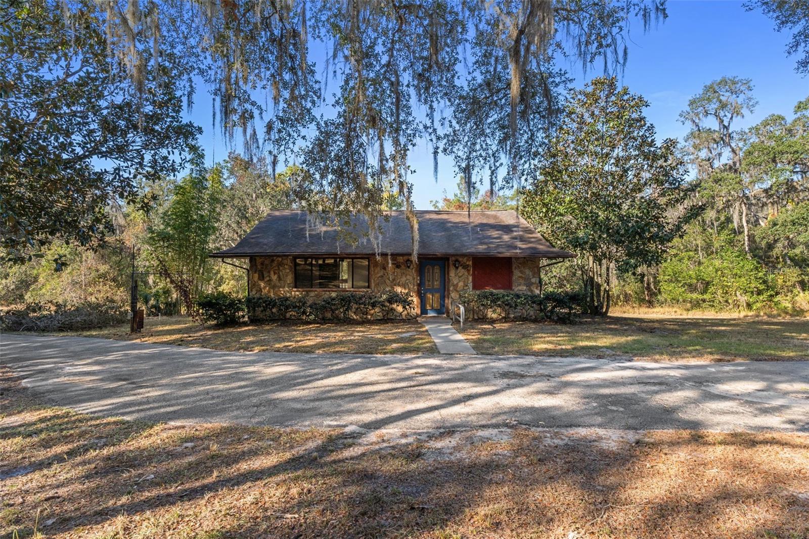 Agricultural Residential  Zoning and exceptionally private. No dirt roads from the highway to your doorstep with over 300 feet of blacktop driveway. Natural Florida beauty on this 4.22-acre property with a spring-fed creek. This rare two-story home features an upper-level entry with a primary suite, two huge balconies,  living room, kitchen, and dining area overlooking the wooded landscape. The lower level—accessible by stairs includes a second primary suite, an oversized family room, and a laundry room, offering excellent flexibility for guests or multi-generational living. Zoning allows for outbuildings and animals.Located in a peaceful area of Brooksville known for its large acreage homes, rolling terrain, and quiet country surroundings, this property provides a true sense of space while remaining convenient to I-75, local parks, nature preserves, and everyday amenities. Enjoy easy access to Croom Wildlife Management Area, hiking/biking trails, farms, and outdoor recreation, all within a short drive.