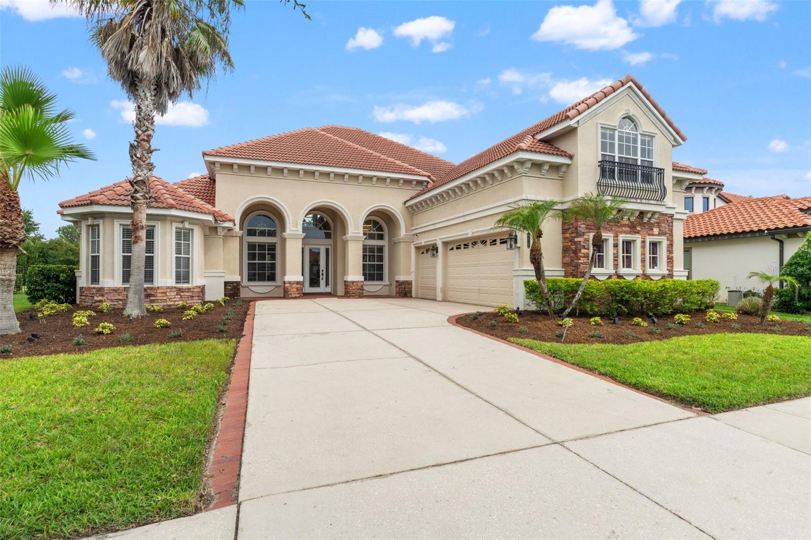 Welcome to luxury living in the prestigious guard-gated community of Grand Hampton! Perfectly positioned on a private conservation homesite, this beautifully updated residence blends timeless Mediterranean architecture with a fresh, modern interior. Offering 5 bedrooms, 5 full baths, a loft, 3-car garage, and an impressive screened pool and spa retreat, this home was designed for both everyday comfort and effortless entertaining.A grand exterior with tile roof, stone accents, lush landscaping, and double glass entry doors creates an elegant first impression. Inside, soaring ceilings, abundant natural light, and wide-plank luxury vinyl flooring set the stage for the home’s stunning modern transformation. The formal living room makes an immediate statement with a dramatic two-story wood-paneled accent wall, adding warmth, texture, and architectural impact. Upstairs, sleek glass railings overlook the main living areas, giving the home a clean, contemporary feel.The open kitchen and family room are light, bright, and beautifully connected to the outdoor living space. The kitchen features white 42-inch cabinetry, granite countertops, stainless steel appliances, a glass tile backsplash, upgraded hardware, pendant lighting, and a large breakfast bar. The adjoining casual dining and family room enjoy walls of windows overlooking the pool, lanai, and peaceful conservation backdrop.The first-floor primary suite is a spacious retreat with tray ceilings, pool views, private lanai access, and dual walk-in closets. The remodeled primary bath feels like a private spa with marble-look flooring, a soaking tub framed by columns, dual vanities, gold accents, and a large glass-enclosed shower.The main level also includes three generously sized secondary bedrooms, one of which is currently being used as an office, offering excellent flexibility for guests, work-from-home needs, or multigenerational living. All bathrooms have been remodeled with sleek, modern finishes, creating a cohesive updated feel throughout the home.Upstairs offers excellent flexibility with a large loft/media space, glass railing views, a wet bar area, access to a private balcony, and one spacious bedroom with an ensuite bath. Whether used as a theater room, game room, guest retreat, or second living area, this upper-level space adds tremendous versatility.Outdoor living is where this home truly shines. The expansive covered lanai opens to a sparkling pool and spa, all enclosed within a grand screened cage and surrounded by paver decking. With conservation views, no rear neighbors, and plenty of covered and open entertaining space, this backyard delivers the privacy and Florida lifestyle buyers are looking for.Located in one of New Tampa’s most desirable master-planned communities, Grand Hampton offers resort-style amenities including a clubhouse, fitness center, community pools, playgrounds, tennis courts, walking trails, and 24-hour guard-gated security.
