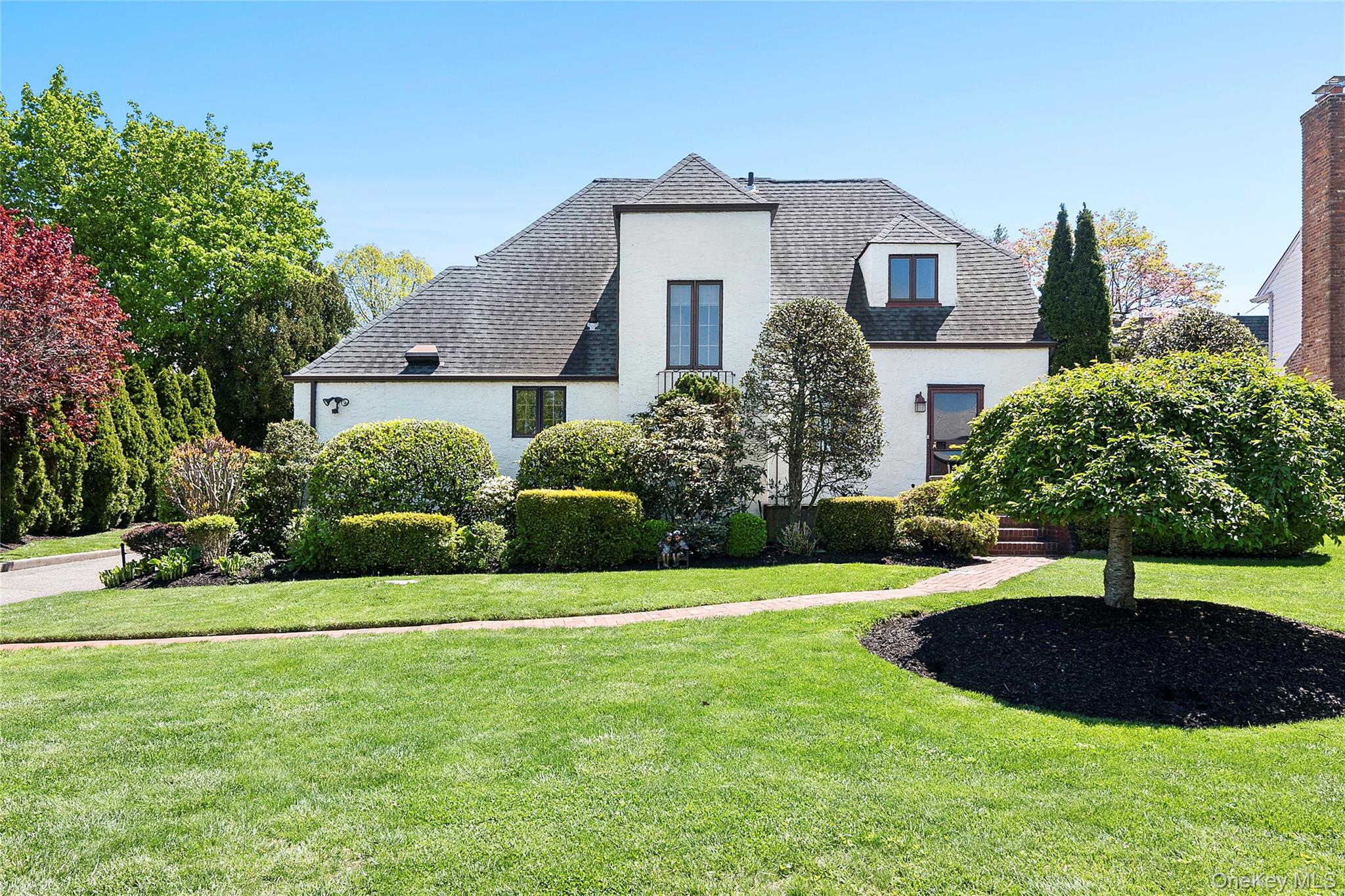 Nestled in the prestigious Bayside Gables—one of North Queens’ most sought-after neighborhoods—this timeless Tudor sits on an oversized 80’ x 103’ lot, offering classic architecture, generous living space, and exceptional curb appeal.The main level features a spacious chef’s kitchen, formal dining room, and an elegant living room anchored by an imported marble wood-burning fireplace. A custom-built library/home office adds sophistication, while the primary suite offers a spacious bath with the convenience of an in-unit washer and dryer. A large entertainment room opens to an enclosed porch, creating an effortless flow for everyday living and entertaining.The second floor offers three generously sized bedrooms and a full bath. The finished basement, complete with a separate entrance and an additional washer and dryer, provides exceptional flexibility for recreation, guest accommodations, or extended living.Beautifully landscaped grounds surround an expansive paved patio, creating a private outdoor retreat ideal for entertaining, dining al fresco, or simply unwinding.A rare opportunity to own a classic Tudor in one of Bayside’s most desirable neighborhoods—offering timeless charm, generous proportions, and the opportunity to personalize the home while enjoying the prestige and convenience of the coveted Bayside Gables community.