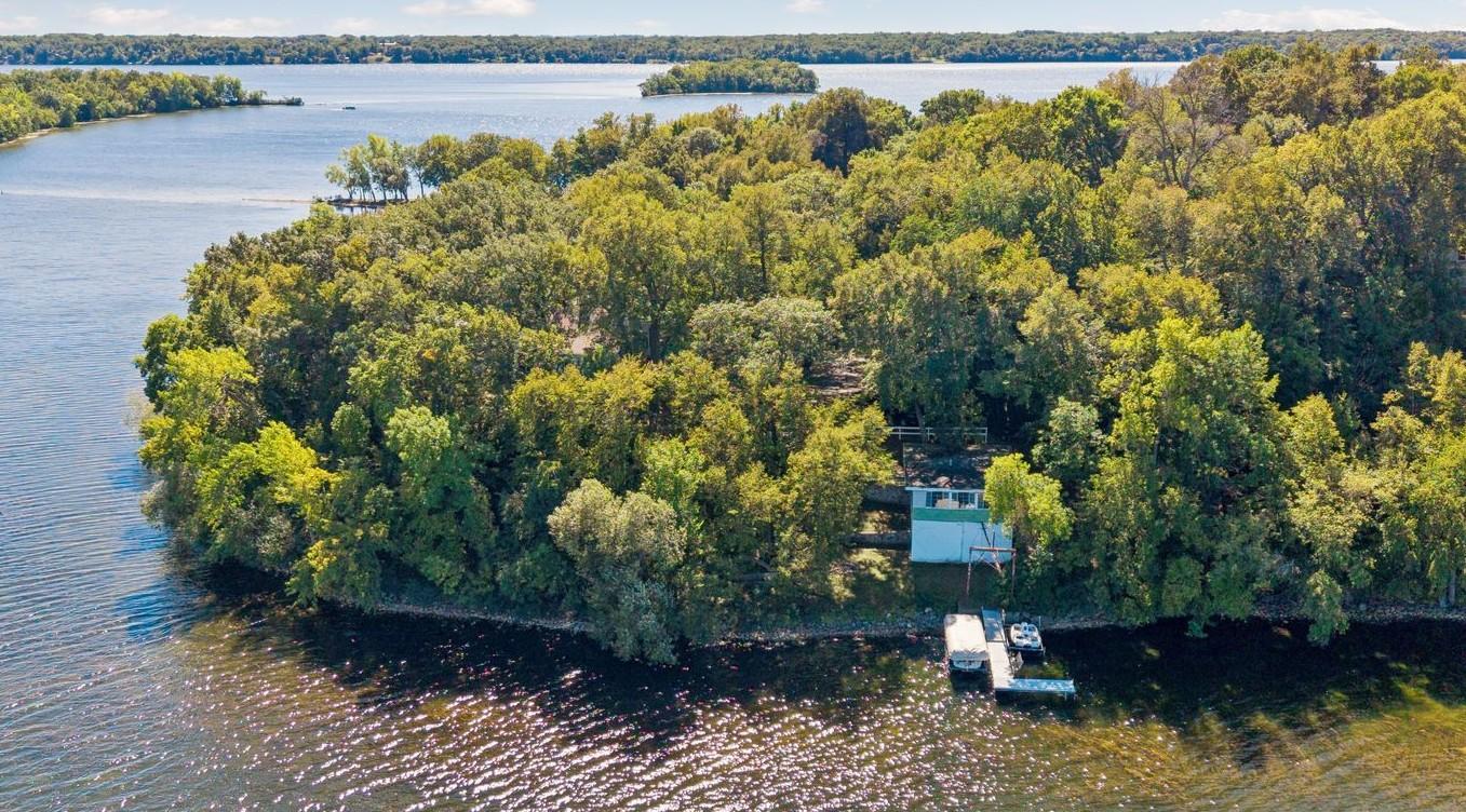 A Rare Lake Koronis Legacy Property. Just 90 minutes northwest of the Twin Cities, this extraordinary property presents an opportunity that is rarely found. Set behind a private gated entrance on 1.65 remarkable acres with approximately 600 feet of hard-sand shoreline, the property feels like a private compound from another era, offering an exceptional combination of land, shoreline, multiple dwellings, and panoramic lake views. Elevated dramatically above the water, the approximately 2,300-square-foot main cabin commands extraordinary panoramic views across Lake Koronis, creating an unparalleled vantage point to experience the lake from every principal living space. A remarkable time capsule, the cabin features a 500-square-foot enclosed porch, a spectacular 25-by-20-foot living room anchored by a massive stone fireplace, four bedrooms, two full baths and a tandem two-car tuck-under garage. Two additional lakefront cottages sit directly at the water’s edge on a level shoreline, offering exceptional flexibility for family and guests. One features a bedroom, kitchen, and full bath, while the second offers two bedrooms, a full kitchen and full bath—each with easy, direct access to the lake. A separate boathouse provides covered boat storage below with a two-bedroom cottage above, creating an extraordinary collection of spaces for guests. The possibilities are extraordinary—create a spectacular new compound or a one-of-a-kind trophy lake property, thoughtfully designed around this exceptional setting, expansive shoreline, and panoramic views. Opportunities with this combination of acreage, shoreline, multiple structures, and location are exceptionally rare. Lake Koronis spans nearly 3,000 acres with approximately 16 miles of shoreline and depths reaching 132 feet, offering outstanding boating, fishing, swimming, and watersport, all just minutes from Paynesville.