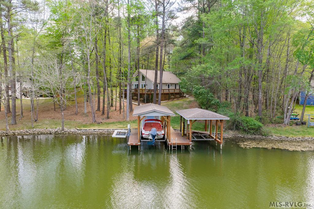 This is a true turnkey offering on Lake Gaston! What a great A-frame home on a flat lot with 3 bedrooms, 3 full baths, 1 flex room, and coming fully furnished. The property has a double boathouse with a wonderful 4.5-5 feet of water at the end and sits in Poe Creek in the highly sought after SE Quad. Just a 5 minute boat ride and you are on the main lake. Per the prior owner in 2023 the house was painted and new gutters installed as well as gutter guards. A new gas pak was installed in 2019. The lot is bulkheaded and because of the location makes for a great swimming area at the dock. No wakes and boat traffic to deal with and no bridges to cross under making your choice of boat unlimited. Top this off with a community pool and community boat ramp so you or your guests can put in other watercraft and it makes this property a must see!