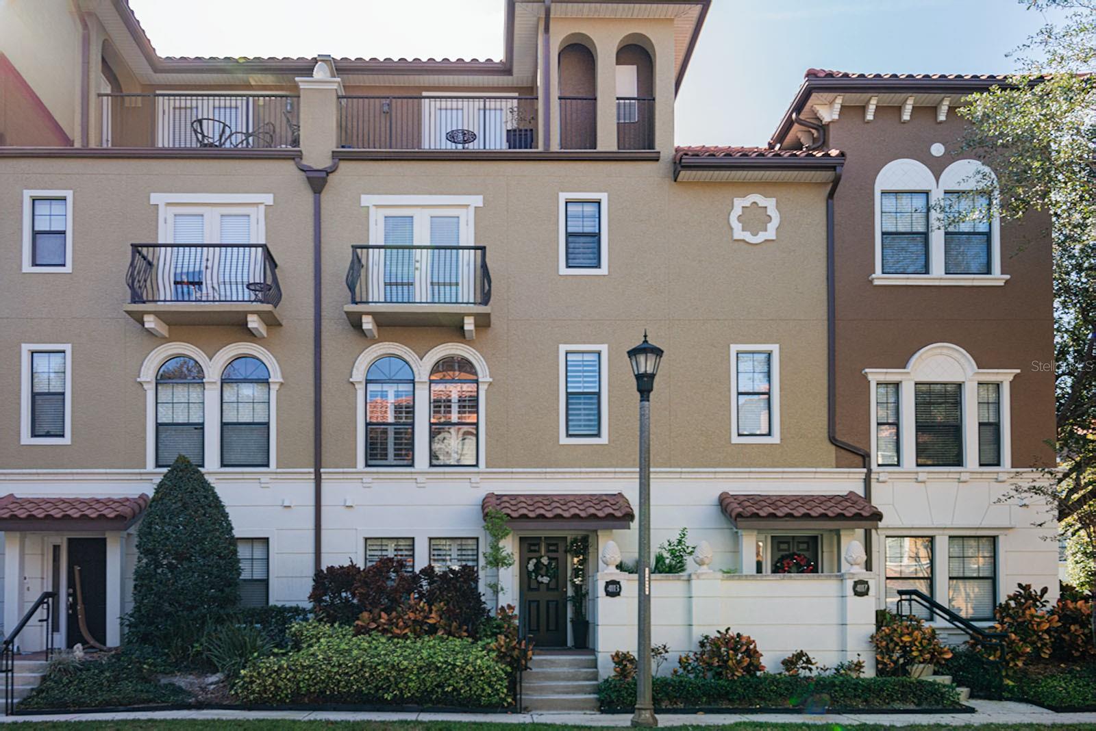 Elevated living meets effortless convenience in the 24-hour guard-gated community of Fountain Parke at Lake Mary. This spacious four-story Mediterranean-style townhome offers an exceptional blend of elegance, versatility, and low-maintenance living—complete with a private elevator servicing every level, a rare and highly sought-after feature.A charming stucco exterior, terracotta tile roof, and inviting front patio framed by mature landscaping set the tone for what awaits inside. Recent updates include fresh interior paint, newer engineered hardwood flooring, and plantation shutters throughout, creating a light, polished atmosphere.The entry level welcomes you with a bright foyer and a private guest suite featuring a full bath with walk-in shower, ideal for visitors, extended family, or multigenerational living. This level also provides access to the two-car garage with custom built-in storage and an installed EV charger—a modern convenience today’s buyers appreciate.The second floor is designed for entertaining, with open living and dining spaces accented by tall arched windows that flood the home with natural light. The well-appointed kitchen features granite countertops, 42” cabinetry, and newer stainless steel Samsung appliances. Step outside to a private balcony with exterior storage, perfect for morning coffee or evening relaxation.On the third level, you’ll find an additional bedroom with generous closet space and tranquil views, along with the primary suite retreat. The primary bathroom offers dual vanities, a walk-in shower, soaking tub, and two custom closets, providing both comfort and functionality.The fourth floor delivers exceptional flex space—ideal as a media room, game room, home office, or additional bedroom—leading to a second balcony and expansive rooftop terrace. Designed for unforgettable gatherings, this outdoor retreat features a full summer kitchen, wet bar, and built-in grill—an entertainer’s dream rarely found in townhome living.Additional highlights include a new HVAC system, ensuring year-round comfort. Fountain Parke residents enjoy resort-style amenities including a pool and spa, tennis and pickleball courts, putting green, dog park, clubhouse, and fitness center. Ideally located near major roadways, shopping, dining, golf courses, and popular attractions, this home truly delivers on location, lifestyle, and luxury.Schedule your private tour today and experience this exceptional home!24-hour notice required. Video and/or audio surveillance with recording capability may be in use on these premises.