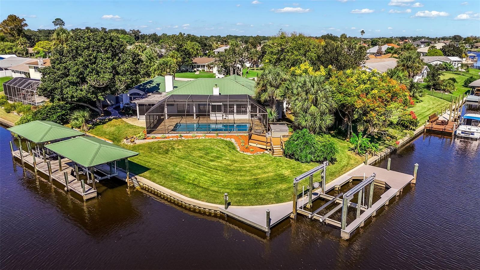 LUXURY WATERFRONT LIVING AT ITS FINEST! Experience the ultimate Florida lifestyle in this exceptional Palm Coast waterfront estate, situated on a rare tip lot with 178 feet of saltwater canal frontage. Offering an extraordinary combination of privacy, elegant living spaces, and premier boating amenities, this property is designed for those who appreciate waterfront living at its best with no HOA.An impressive stamped-concrete driveway welcomes you home. Inside, the expansive open-concept layout features a spacious family room with a wood-burning fireplace and a beautifully appointed kitchen with custom granite countertops, a matching granite backsplash, double ovens, and a gas cooktop. French doors open to a spectacular outdoor retreat overlooking the tranquil canal.Designed for year-round enjoyment and entertaining, the backyard showcases a summer kitchen with a built-in stainless-steel grill, an oversized covered patio, a heated saltwater pool, an expansive pool deck, and a 5-person Caldera spa. Multiple bedroom suites include two primary suites, with one featuring a luxurious walk-in shower and private sauna. Additional highlights include a dedicated theater room, a separate waterfront office/hobby room, hardwood bedroom flooring, crown molding, inside laundry, and an oversized garage with abundant storage. The entire interior has been professionally painted, and one AC unit was replaced in 2024.Boating enthusiasts will appreciate the exceptional waterfront infrastructure, including two covered boat houses, an 8,000-pound boat lift, an 8,000-pound jet ski lift, and a dock equipped with water and electric. The newer composite dock, completed in 2024, features an impressive 25,000-pound boat lift. All lifts are US Boat Lifts. A convenient fish-cleaning station makes preparing your daily catch easy, while a separate shed is equipped with water and electric and ready for a commercial ice maker.The fully fenced yard, mature landscaping, and extensive outdoor amenities create a private waterfront sanctuary with convenient access from the saltwater canal to the Intracoastal Waterway. Spend your days cruising the waterways, entertaining poolside, relaxing in the spa, or enjoying the many possibilities this remarkable property offers.This is more than a home-it’s a private waterfront retreat where luxury, leisure, and the Florida boating lifestyle come together.