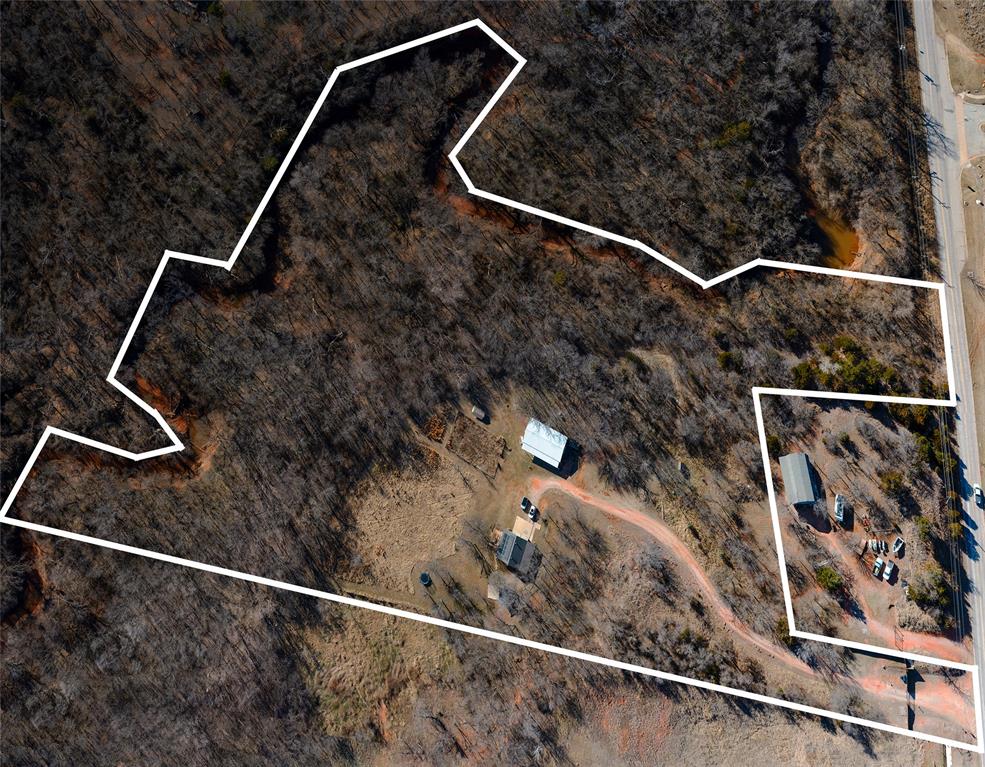 Fantastic opportunity to own 10.210 wooded acres in a prime location just off N.E. 122nd Street and Eastern Avenue, perfectly positioned on the edge of Oklahoma City and Edmond with easy access to the Turnpike and I-35. This rare, estate-level parcel offers exceptional privacy, natural beauty, and unlimited potential. The property features a 744 SF (MOL) home with 1 bedroom and 1 bathroom, a barn and an additional 160 SF (MOL) studio space. Utilities are already in place with a septic system and water well, including a new pump and tubing. A private drive with keypad/remote gated entry provides added security and seclusion. Backing to a scenic creek, the land showcases stunning natural rock cliffs, mature Persimmon and Black Walnut trees and abundant wildlife, creating a peaceful, park-like setting. This is an ideal site to build your dream home, create an equestrian estate or design a legacy property that embraces the natural topography and conservation-minded living. Offered as-is, with primary value in the land. Opportunities like this are rare - protected, irreplaceable acreage in a highly desirable corridor with utilities in place and development nearby. Perfect for buyers seeking privacy, multi-generational living potential, studio or workshop flexibility, or long-term land investment in a rapidly growing area. House is being sold as-is and is currently being leased.