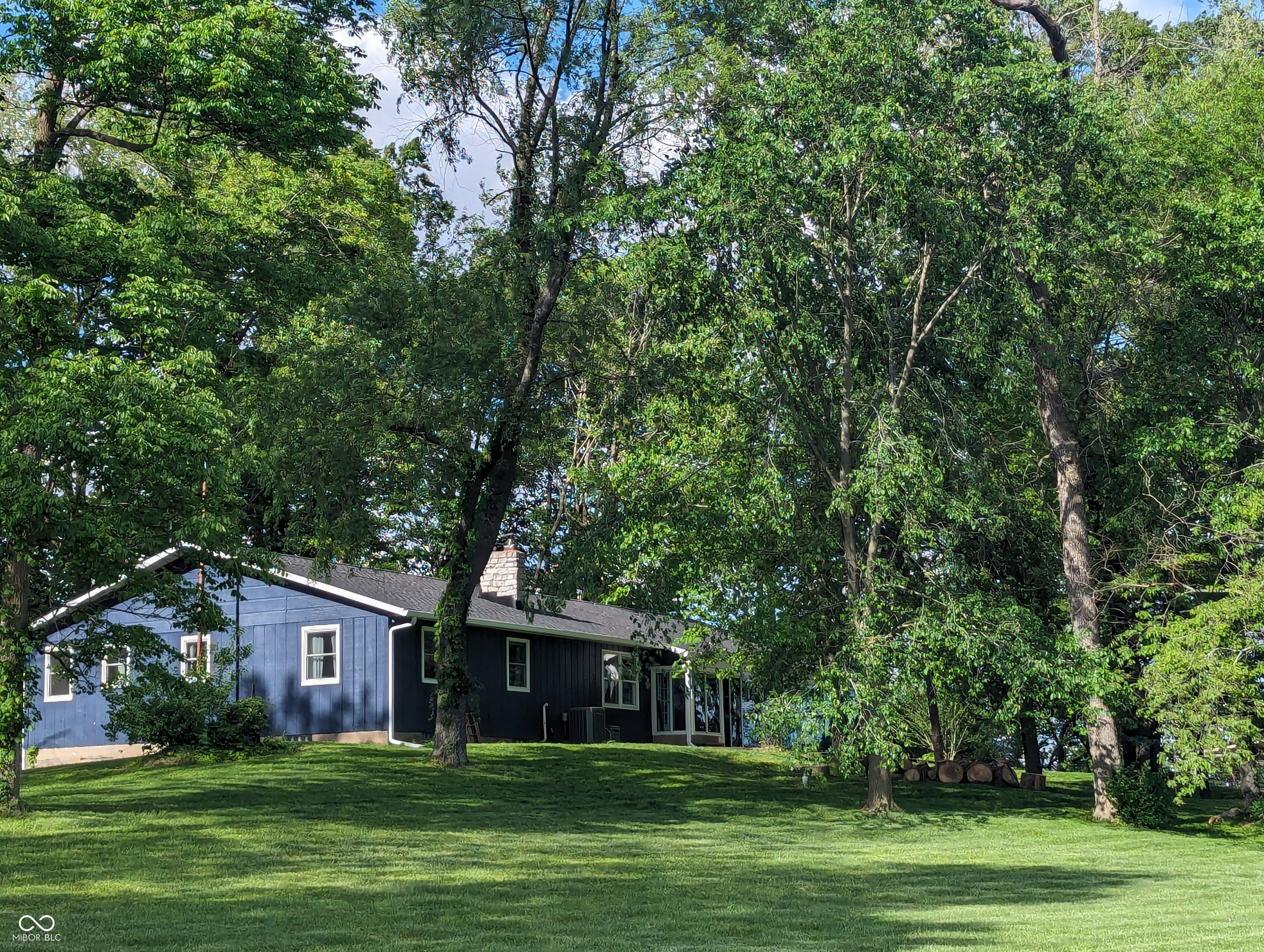 Set on a beautiful 3 acre parcel this thoughtfully updated ranch offers a rare blend of privacy, space & everyday convenience, all just 2 minutes from shopping, dining & easy highway access. Properties with this amount of land so close to town are increasingly hard to find. The main level features hardwood floors, a bright & welcoming layout with abundant natural light. A spacious sunroom overlooks the serene setting & provides a seamless connection between indoor living & the surrounding landscape. The kitchen is both functional & refined featuring matching GE Profile appliances, custom cabinetry & granite countertops, designed for comfortable daily living & entertaining. The finished basement expands the home's versatility with a home theater area, wet bar, large private office &  half bath, ideal for remote work, hobbies, or hosting guests. With 3 bedrooms & 2 full plus 2 half bathrooms, the layout offers flexibility & comfort throughout. Recent exterior improvements include a new roof, seamless gutters with guards, new fiberglass windows & refreshed exterior paint. Major mechanical updates such as a newer HVAC system, water heater, water softener & updated electrical components provide peace of mind. Outside, the land truly sets this property apart with mature trees, newly planted evergreens, fruit trees, garden space & a large fire pit. A barn with 2 large animal stalls, updated electric, lighting & a 220 amp outlet, ideal for hobby farming, livestock, or workshop use.  As well as a separate chicken coop, this home offers endless possibilities. This is acreage living without the tradeoffs of a remote location. Extensive improvements inside & out make this a rare opportunity to enjoy acreage living without sacrificing convenience. **CR 400 N is also called Paul Hand Blvd, this is better using maps apps.