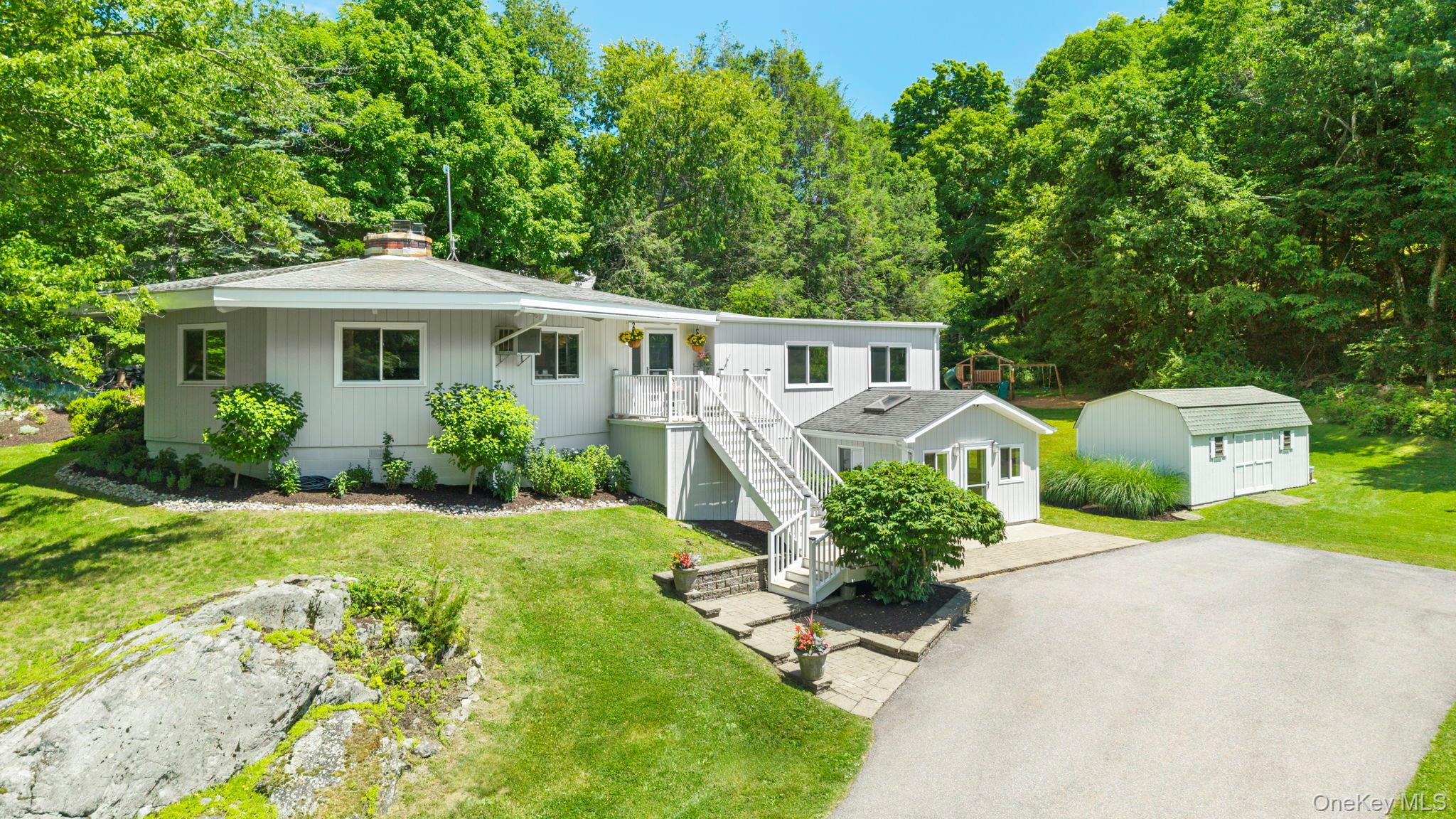 Rare opportunity to own a truly distinctive contemporary ranch set atop one of the highest elevations in Westchester County. Showcasing an architecturally unique octagonal design, this home offers a level of character and presence rarely found in today’s market. Filled with natural light, the main level features soaring vaulted ceilings and an open-concept floor plan designed for both comfortable everyday living and effortless entertaining. The thoughtfully designed layout flows seamlessly throughout, with each room cohesively integrated into the home’s striking architectural form. The updated kitchen serves as the heart of the home, while three spacious bedrooms are conveniently located on the main level. The primary suite offers two generous closets and an en-suite bath. The finished lower level expands the home’s versatility with impressive vaulted ceilings, a full bathroom, a private office, and a substantial bonus living space. A separate finished room offers exceptional flexibility for guests, a home gym, a creative studio, or additional guest space. Situated on a full acre of usable property, the grounds provide ample space for outdoor entertaining, gatherings, and recreation. Enjoy peaceful privacy, summer barbecues, and breathtaking sunset views from this exceptional hilltop setting.