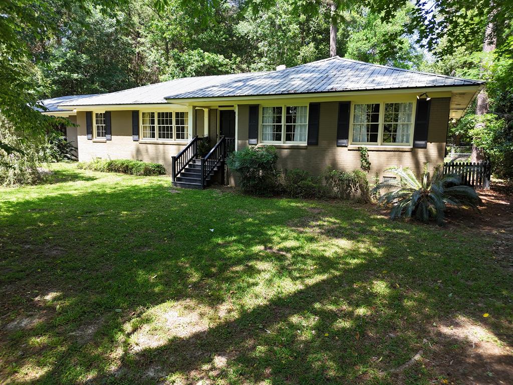Spacious midcentury, all brick home, nestled in a serene  wooded area in the one of Thomasville's most desirable established neighbors, just a short walk or golf cart ride form downtown! Approximately 2,652 Sq ft, 4 bedrooms, 3 full baths, massive formal living room, dining room, fireside paneled family room with adjoining sunroom, ideal for entertaining and in door recreation area. Primary suite with updated bath and walk in shower, and walk in closet. Kitchen has gourmet gas range with attached laundry and mudroom with plenty  for freezers, pet space, office or gym with  storage and laundry sink. Outside, the nearly acre lot is the ultimate in privacy for in town living. Fully fenced and gated, with outdoor living space and natural mature, wooded landscaping  and the ambience of mountain living just off the patio, with nearby attached double carport. Many updates such as  all metal roof, recent HVAC system, renovated original hardwood flooring, complete with updated flooring joist and utility basement. Call today to schedule your personal tour.