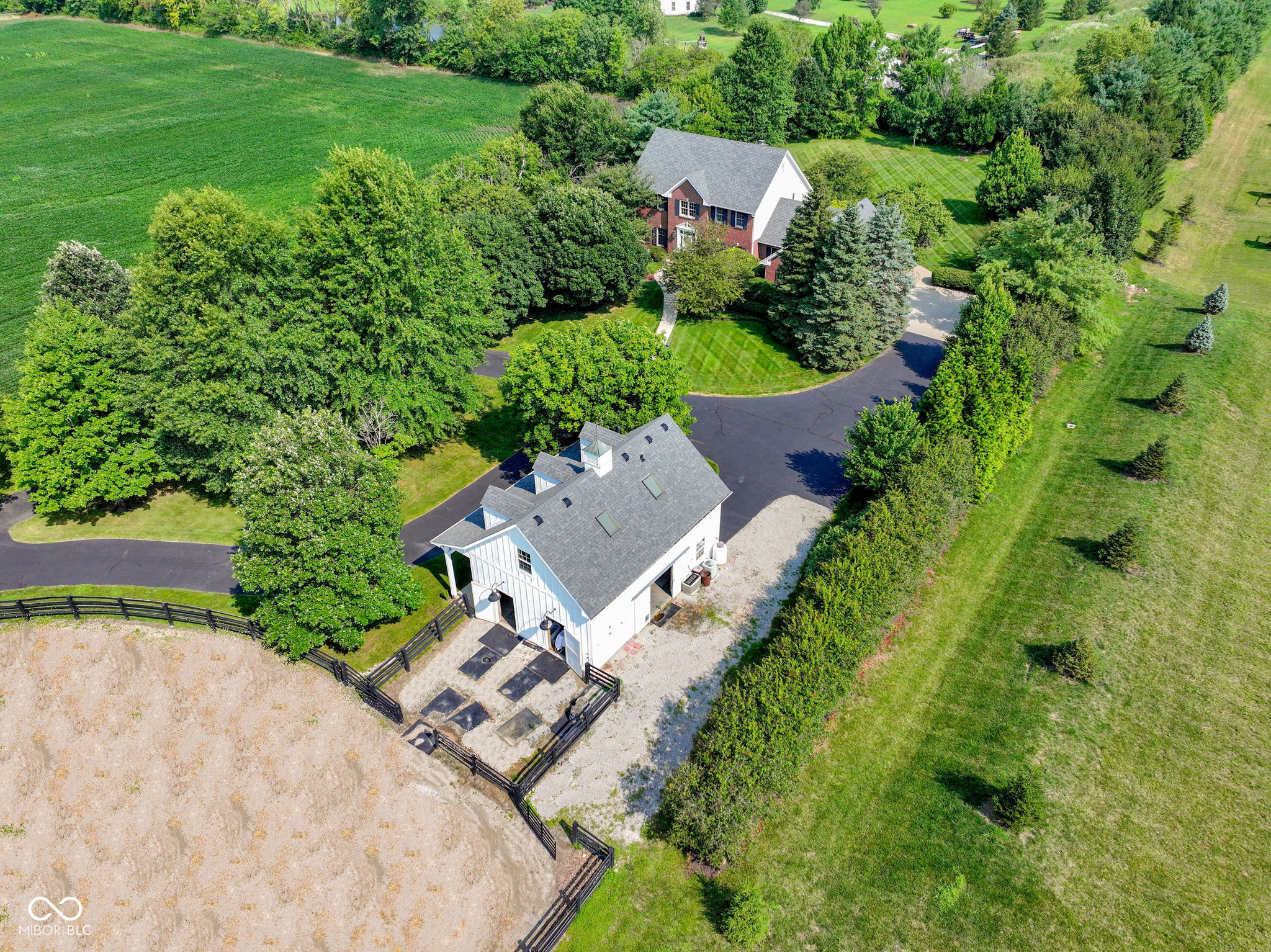 Rare opportunity to own 5 plus acres in Zionsville schools. Tucked away along a picturesque winding driveway, this custom-built full-brick home is surrounded by a variety of mature trees that provide remarkable privacy and scenic views that change beautifully with the seasons. Inside, the home feels warm and comfortable, with hardwood floors and inviting spaces throughout. The main-level primary suite offers a quiet retreat, complete with a beautiful ensuite bath and a hallway that connects directly to the home office. With French doors, built-in shelving, and plenty of natural light, the office is a great spot to work from home, read, or simply enjoy a quiet moment. The vaulted great room is the heart of the home, centered around a beautiful brick fireplace and open to the kitchen, creating an easy flow for both everyday living and time spent with family and friends. Upstairs, three spacious bedrooms share a full bath and provide plenty of room for family or guests. The finished lower level adds even more flexible living space, with a fifth bedroom, full bath, wet bar, and a large recreation area that works well for movie nights, workouts, or casual entertaining. The property's barn adds tremendous flexibility and opportunity. Currently outfitted with two stalls, automatic waterers, hay storage, and a tack area, the space could easily accommodate horses, hobby farming, small animals, a workshop, studio, or additional storage. A finished apartment above the barn with a kitchenette and full bath offers excellent space for guests, extended family, or a private office. The possibilities are endless! Minutes from Zionsville schools, shopping, dining, and interstates, this property is a rare opportunity to enjoy peaceful country living without sacrificing modern conveniences. Whether you're dreaming of horses, hobby farming, or a retreat from everyday life, this property is ready to bring your vision to life.