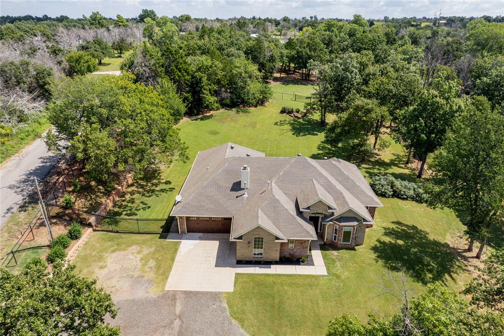 Set on 4.7 beautifully landscaped acres, this custom-built estate combines timeless design with modern convenience. A double-gated entry—one keypad, one key-card—welcomes you into a property that is fully fenced and sectioned with iron gates for privacy and security. Inside, the home features stone tiles and wood flooring, 10-foot ceilings with crown molding, and elegant accent columns. A private office with French doors, full mudroom with wash bin, and cabinetry throughout provide both style and function.

The living room features a wood-burning fireplace with custom mantle and built-in electronics cabinet space, while unique chandeliers in the entryway and remote-control ceiling fans add to the home’s refined details.

The kitchen is a true highlight, offering all-chrome Samsung appliances, a five-burner gas stove with microwave electric oven, dishwasher, garbage disposal, granite countertops, tile backsplash, and ceiling-height cabinetry with breakfast bar. The adjoining dining area, canned lighting, and pendant fixtures create the perfect space for entertainment.


The primary suite includes an elevated ceiling, custom sliding barn doors, dual walk-in closets with built-ins, and a spa-like bath with double vanities, private toilet room, oversized walk-in shower, and a large soaking tub. Three guest bedrooms each include fans and bay security windows, with walk-in closets in two rooms. The main guest bath offers dual sinks, private tub/toilet area, and extra cabinetry. A granite powder bath is perfect for visitors.

Additional features include large 3-car garage, garage flooring is sealed & textured with an attic lift, Kohler backup generator, gated back patio and gas hot tub, and alarm system for peace of mind! This property blends luxury finishes with everyday practicality—an exceptional opportunity to own a move-in ready estate on nearly 5 acres.