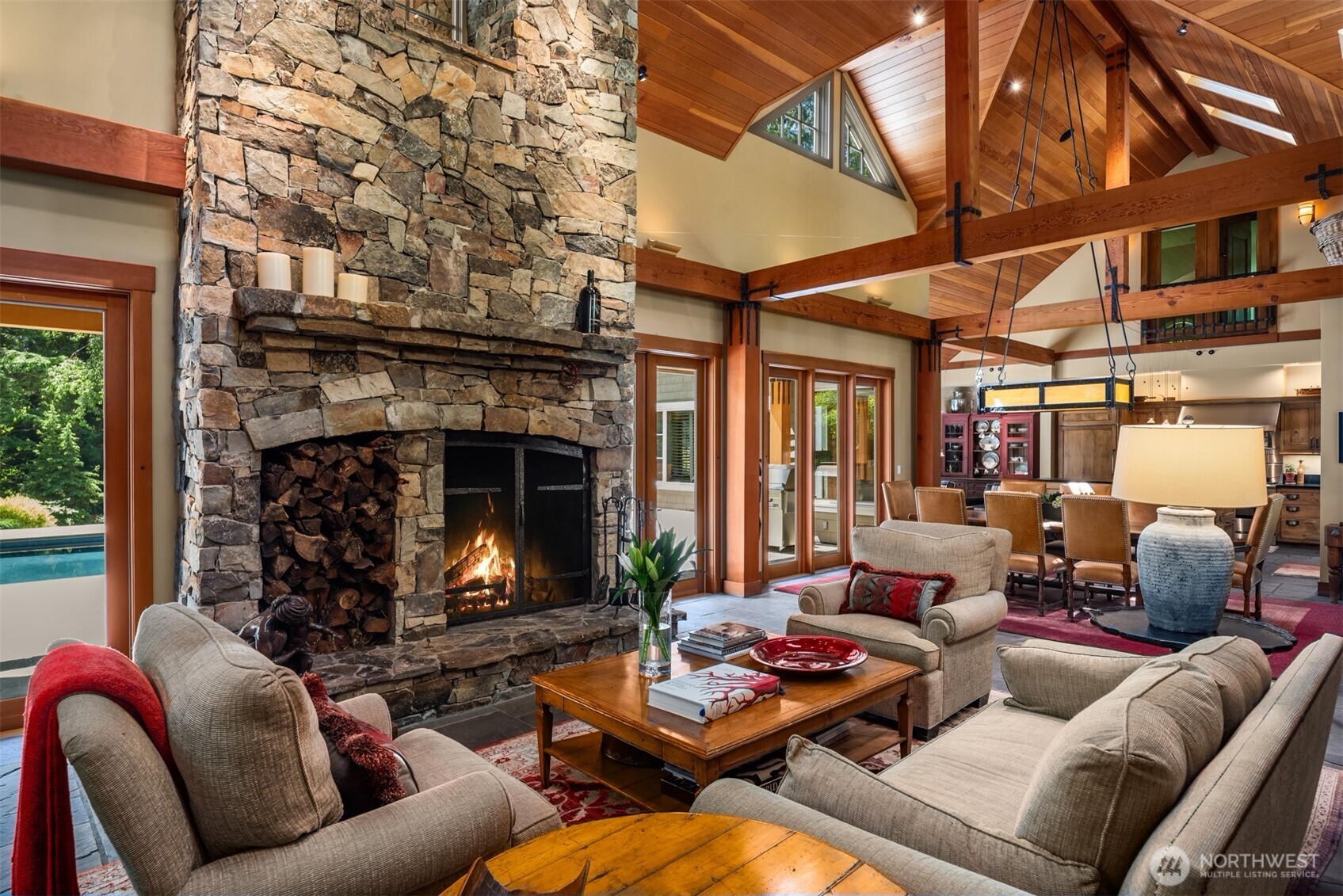 Living room with stone fireplace, vaulted wood ceiling, and seated area