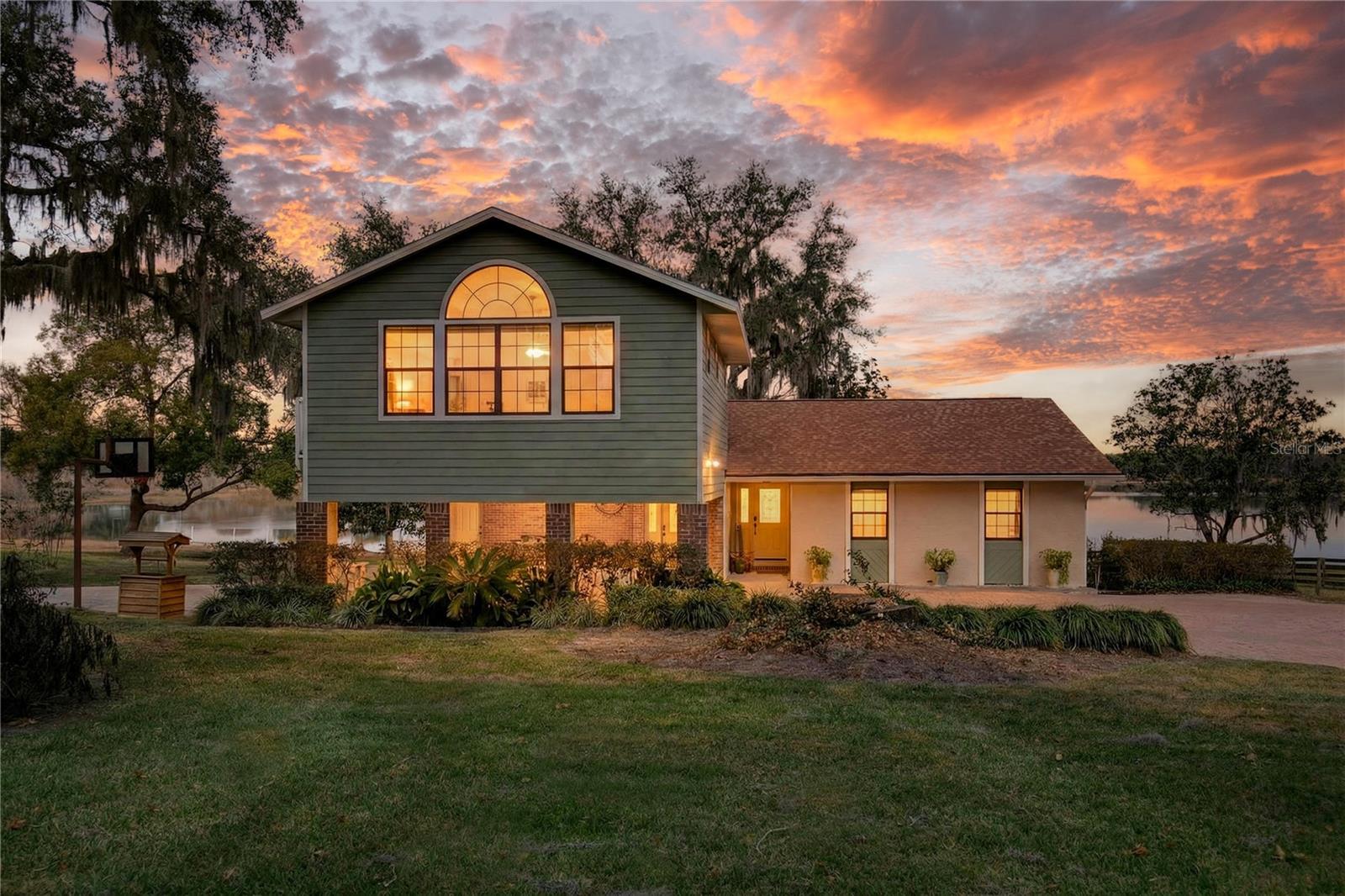 Set on a stunning almost 90 acre private ski lake, this beautifully maintained lakefront home offers breathtaking water views, deep water access and an ideal blend of space, comfort, and lifestyle. Enjoy boating, skiing, fishing, and unforgettable sunsets right from your own backyard.A newly added primary bedroom retreat provides a private sanctuary with generous space and an en-suite bath, creating the perfect owner’s escape. On the first floor, a bedroom with its own bathroom and private balcony previously served as the primary suite and is ideal for in-law living, guests, or multi-generational use.One of the secondary bedrooms features a charming loft accessed by ladder, complete with a skylight — a delightful fort-style space perfect for little ones or creative use.The kitchen is thoughtfully designed with a custom eat-in area, granite countertops, and ample cabinetry, offering both functionality and warmth for everyday living and entertaining. The living room is filled with natural light, anchored by a wood-burning fireplace, and overlooks the lake, creating an inviting and peaceful gathering space.Additional living areas include a large bonus room, flex room, and a dedicated gym area, providing endless options for work-from-home, hobbies, or recreation.Recent upgrades offer peace of mind, including a new roof (2023), new appliances (2024), three A/C units total, main unit replaced in 2025, a 2019 water heater. The property also features a newer drain field.Outdoors, the property truly shines with full irrigation sourced from the lake, mature landscaping, and expansive open space. The dock includes power, and easy water access, while the carport provides covered storage for vehicles, water toys, or equipment along with a one car garage.This rare lakefront property offers space to live, play, and relax — combining modern updates, flexible living options, and incredible water views in a peaceful Umatilla setting.