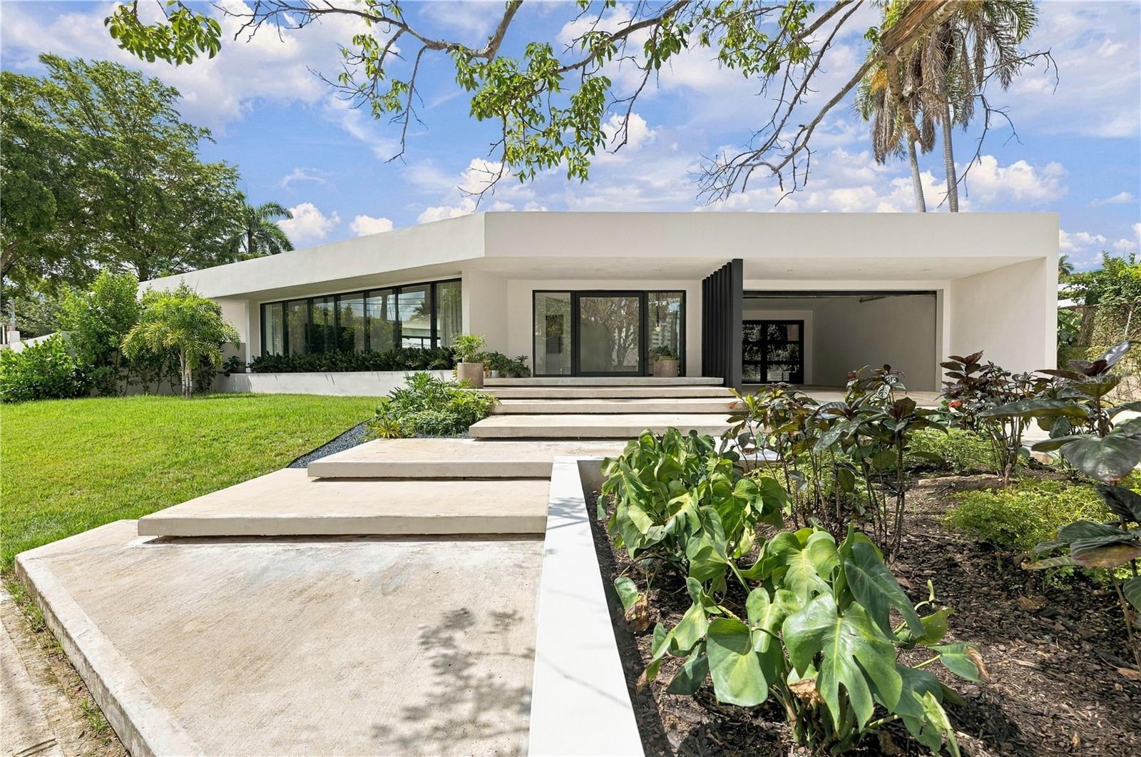 Introducing an in neighborhood rare to market architectural offering in the heart of Garden Hills North, Guaynabo. A single-story open floor plan residence, this Tropical Modernist reconstruction was completed in October of 2026 and fully turn key in anticipation of its new owners. From stud to beam, each and every element of K16 Garden Hills North has been thoughtfully considered with equal intention, to inspire a space dominated by love. From the soft earth tones to the natural stone and wood accents throughout, each inspired design detail carries weight in the home's visibly well constructed bones. Offering an impressive 1,000 sq.m parcel with a total build out of 7,422 sq. ft  of which 3,688 sq.ft are air conditioned, this 4 bedroom 4 and a half bath home is an oasis highlighted by the gourmet outdoor covered summer kitchen, patios for dining and sunning, and frame worthy black bottomed pool. The graciously sized secondary bedroom suites open onto the home's green spaces, each with its own access to the garden and beyond. The primary, at an exciting 750 sq.ft, is a private wing unto itself, appointed with a custom wood-framed media wall, 15 ft pent ceiling, true oversized walk in closet, and double shower set with free standing soaking tub, highlighted by the glorious sky lights bathing the space in subdued light throughout the day. Honed stone surfaces, warm wood millwork, and a quiet considered color story carry through every room, uniting the residence under a single, deliberate vision. A two-car double height covered garage with gate and paved driveway accommodating a further two vehicles, complete the homes offering. Fully furnished and turn-key, K-16 Garden Hills North has few to none comparable and available, in Guaynabo.