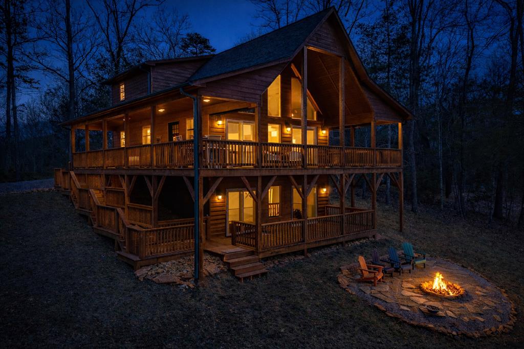 This immaculate chalet is tucked among the trees and designed for slowing down and truly soaking it all in. With multiple levels, a wraparound deck, and a cozy firepit area, there's always a perfect spot for morning coffee, sunset hangs, or simply listening to the woods do their thing. Recently freshly stained on the exterior, the home feels just as inviting on the outside as it does within.  Inside, warm wood finishes, cathedral ceilings, and oversized windows create that classic mountain-chalet feel, while the open living space—kitchen, dining, and living room—keeps everyone connected. The main level offers a comfortable bedroom and full bathroom, ideal for guests or one-level living.  The oversized primary suite in the loft is a true retreat, featuring a spacious walk-in tiled shower and peaceful treetop views. Downstairs, the basement is perfect for hosting guests or working remotely, with a family room, enclosed office or bonus room, and a third full bathroom with an additional walk-in tiled shower.  A brand-new, high-spec garage with a metal roof and custom door provides excellent space for gear, tools, or all your mountain toys, and the property includes a 30-amp RV hookup for added flexibility. Modern conveniences blend seamlessly with rustic charm, including a smart thermostat and high-speed fiber-optic broadband, making full-time living or remote work effortless.  Located within a gated community, this home offers privacy and peace of mind while remaining ideally situated just 10 minutes from the John C. Campbell Folk School and approximately 15 minutes from downtown Murphy. Enjoy easy access to local culture, dining, shopping, and events—while still feeling wonderfully tucked away.  Whether you're looking for a weekend escape, a full-time residence, or a place that simply feels right, this chalet checks every mountain cabin box—and then some.