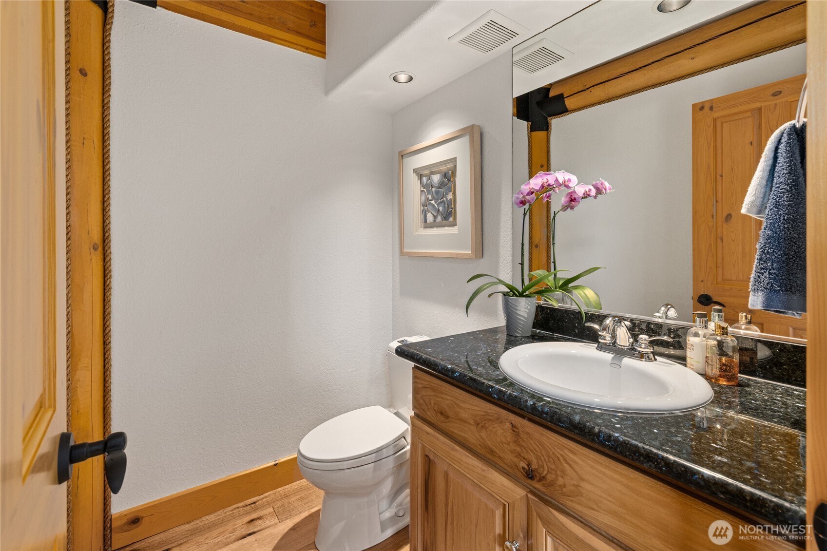 Main-level powder room with granite countertop and warm wood cabinetry.