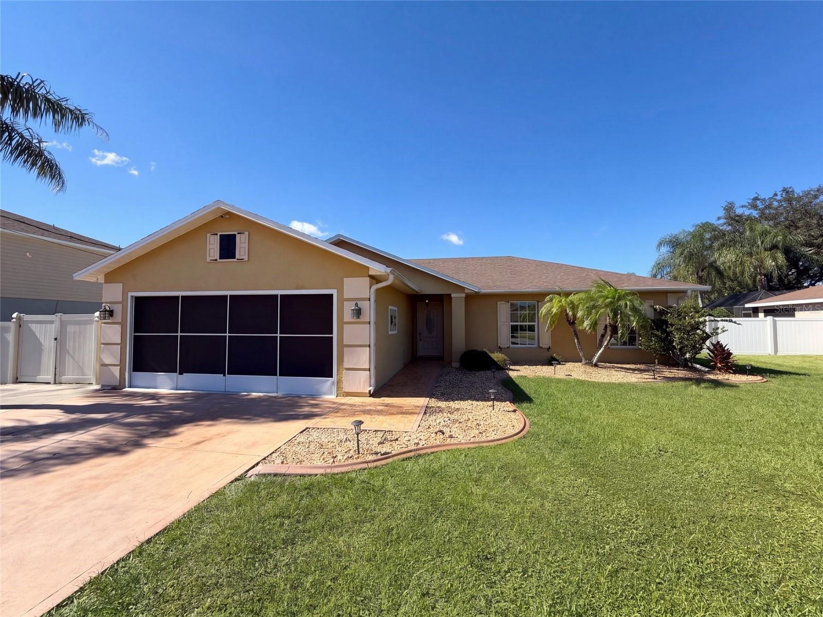 22 Firethorn Ln is a one-story Palm Coast home with a screened, covered patio connected to the main living area. The galley kitchen pairs stainless steel appliances with cabinetry along both sides and a counter opening toward the adjoining space. A high ceiling gives the central living room an open feel, while French doors lead to the screened outdoor area. Set at the rear of the home, the primary bedroom includes a walk-in closet and an adjoining bathroom with a walk-in shower and built-in bench. Secondary bedrooms share a hall bathroom. An attached two-car garage includes shelving and a laundry hookup area. Included 100-Day Home Warranty with buyer activation