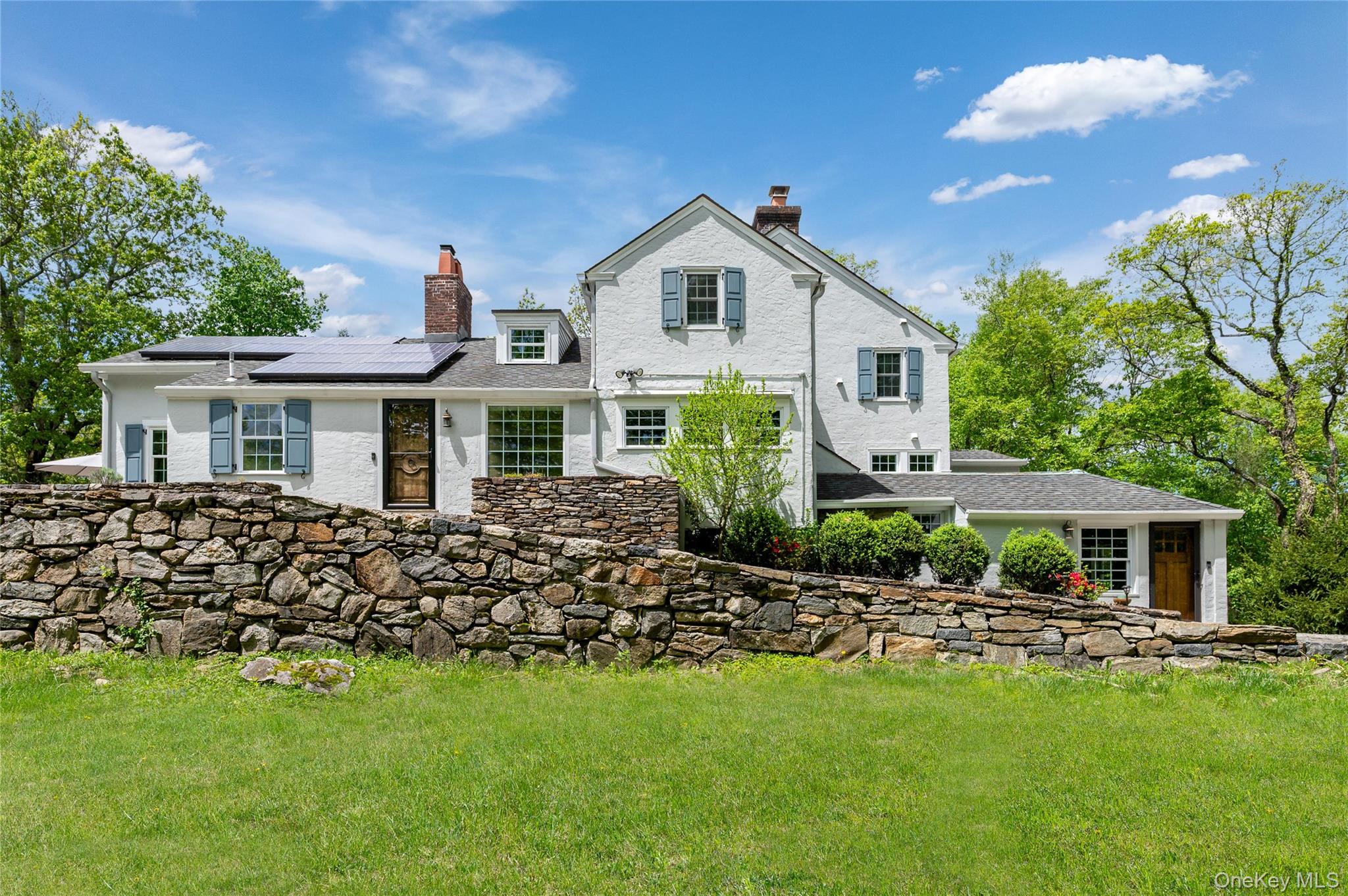 Welcome to 58 Spring Lane – A stunning chalet-style retreat nestled at the end of a private lane just a short walk from the town of Chappaqua and Metro North train. This special home exudes timeless elegance and abundant period charm with its cathedral-vaulted ceilings, original gothic doors, expansive windows and versatile entertaining spaces. The main floor primary suite is a true sanctuary – like waking up in a forest canopy – and features an adjoining room with pocket doors ideal for a home office, nursery, or sitting area. Upstairs, three additional spacious bedrooms and full bath are complemented by a delightful nook, perfect for storage or a whimsical playroom. Abundant, well-outfitted closet spaces are found throughout the home. Entertain with ease in the beautifully updated kitchen with custom cabinetry and high-end appliances, all encompassing sleek finishes that blend modern appeal with classic charm. Don't miss the expansive pantry cabinets with swing-out doors, allowing for ample storage. Powder room located conveniently off the kitchen adjacent to the front door. An oversized dining area off the kitchen offers a gas fireplace and expansive views to the backyard with amazing natural light. Enjoy cozy evenings and effortless entertaining options in the cathedral-like living room with palladian-style windows and direct access to an outdoor wrap-around stone terrace – perfect for hosting meals and watching sunrise/sunset. Other highlights of the home include an outfitted workshop (formerly garage) with built-in shelving and side entry, and a finished walk-out lower level with a wet bar offering multiple options for a family room, gym, playroom, or home office. Stone terraces and a wooden deck with views of the backyard offer ample entertaining options. Comfort and sustainability abounds with the home's 10.6KW solar panel array and Unico small-duct, high-velocity central heating, ventilation and air conditioning technology. This private oasis with gated-entry borders preserved land with direct access to a private trail leading to Pinecliff Audubon Sanctuary. With effortless access to the Saw Mill Parkway for a direct route into New York City, this home remains entirely tucked away—shielded by a dense forest preserve that keeps it entirely out of sight and wrapped in quiet serenity. Walking distance to town and train. A truly one-of-a-kind offering that is not to be missed.