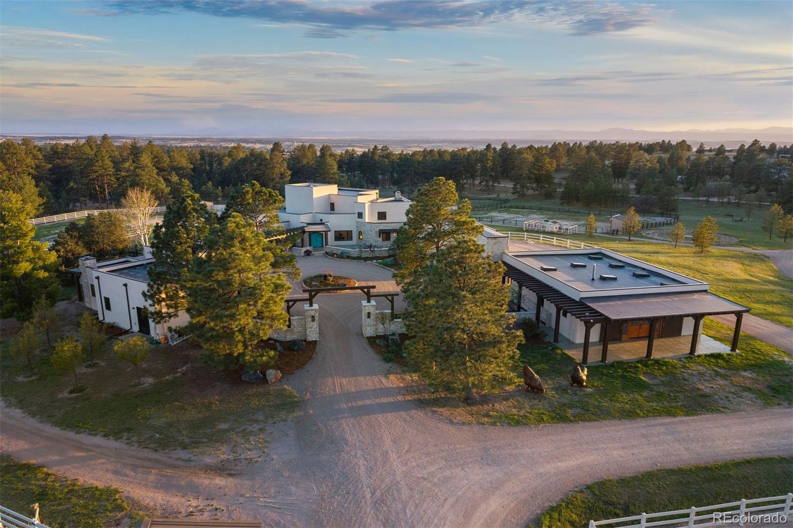 40 acres bordered with hundreds of towering Ponderosa pines, where world-class equestrian infrastructure and a masterfully remodeled desert contemporary residence converge into something that simply cannot be recreated. With 8,900 finished SF., there's plenty of room for living, guests, & indoor recreation. The stable houses 12 heated stalls with tack rooms, wash bays, & a 200x70 indoor arena. A long drive winds through green pastures outlined by white fencing. A gate opens onto a circular motor court anchored by the residence and the separate guest casita. Symbolic arched turquoise doors are custom made, nail-studded, sourced from Corrales, NM.A contemporary home enriched by authentic Southwestern details, including vigas, latillas, hand-carved columns, & a kiva fireplace. Inside, wood floors, Wolf & Sub-Zero appliances, quartz countertops, & a den lined with river stone speak to a home that respects its architecture while not limited by it.  The wraparound patio, shaded by pergolas, flows from the kitchen & great room to the primary suite. The front courtyard, framed by stacked stone walls, offers a linear gas fire pit.The casita is a small luxury home in itself, featuring a kitchen, laundry, & private patio. The Game Barn offers 1,700 SF. of heated recreation space. The complete stable features 20 stalls & 3 tack rooms with a lounge & laundry. The indoor arena offers all-organic footing widely regarded as among the finest available. Outdoor arena, 11 paddocks, & archery range to 120 yards complete the facility.Offering the security & privacy of a gated community without the neighbors — a one-third-mile drive with no public road frontage, electric gated entrance, perimeter fencing, motion-activated video surveillance, & professionally monitored alarm system. No HOA or covenants. 25 mins from DTC, 10 mins from Colorado Horse Park, all via paved roads. The property presents alternative income-producing opportunities.