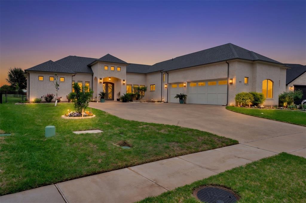 Welcome to Luxury Living in the Heart of Harbor Lakes! Nestled behind the gates of the prestigious Harbor Lakes community, this stunning golf course residence commands attention from the moment you arrive. Sweeping custom landscaping, manicured grounds, & dramatic uplighting frame an exterior that exudes timeless elegance — crowned by a grand double iron-and-glass entry that sets the tone for what awaits inside. Step through the front doors & into a home where every detail has been thoughtfully curated. Soaring 11-foot ceilings, rich champagne engineered oak floors, & crown molding throughout create an atmosphere of refined sophistication. The open living area centers around a gas log fireplace encased in custom faux-marble cast stone, while automated shades offer effortless ambiance at the touch of a button. The chef's kitchen is nothing short of extraordinary- outfitted with Wolf appliances-36in induction cooktop piped for gas, combi steam oven, a Miele dishwasher, & a grand stained island topped in Cambria quartz with a farmhouse sink. Custom white shaker cabinetry with soft-close hardware, lighted floating shelves, & 3D glass tile backsplash complete this culinary showpiece. Retreat to the primary suite, where a 15 x 15 tray ceiling with soft mood lighting, a spa-inspired walk-in shower with dual heads, & a 9' x 11' custom closet with wardrobe lifts & built-in storage make every morning feel like a five-star experience. The oversized 3-car garage features an epoxy floor, dedicated workspace & a staircase leading to a fully encapsulated, insulated walk-in attic with over 570 sq ft of floored storage-a rare find. Additional highlights include a whole-house hardwired alarm system (Wi-Fi enabled), tankless gas water heater, dual-zoned 5-ton Trane heat pump, full front & back sprinkler system, whole-house gutters, surround sound & exterior outlets wired for holiday lighting with a convenient garage timer. This is more than a home — it's a lifestyle.