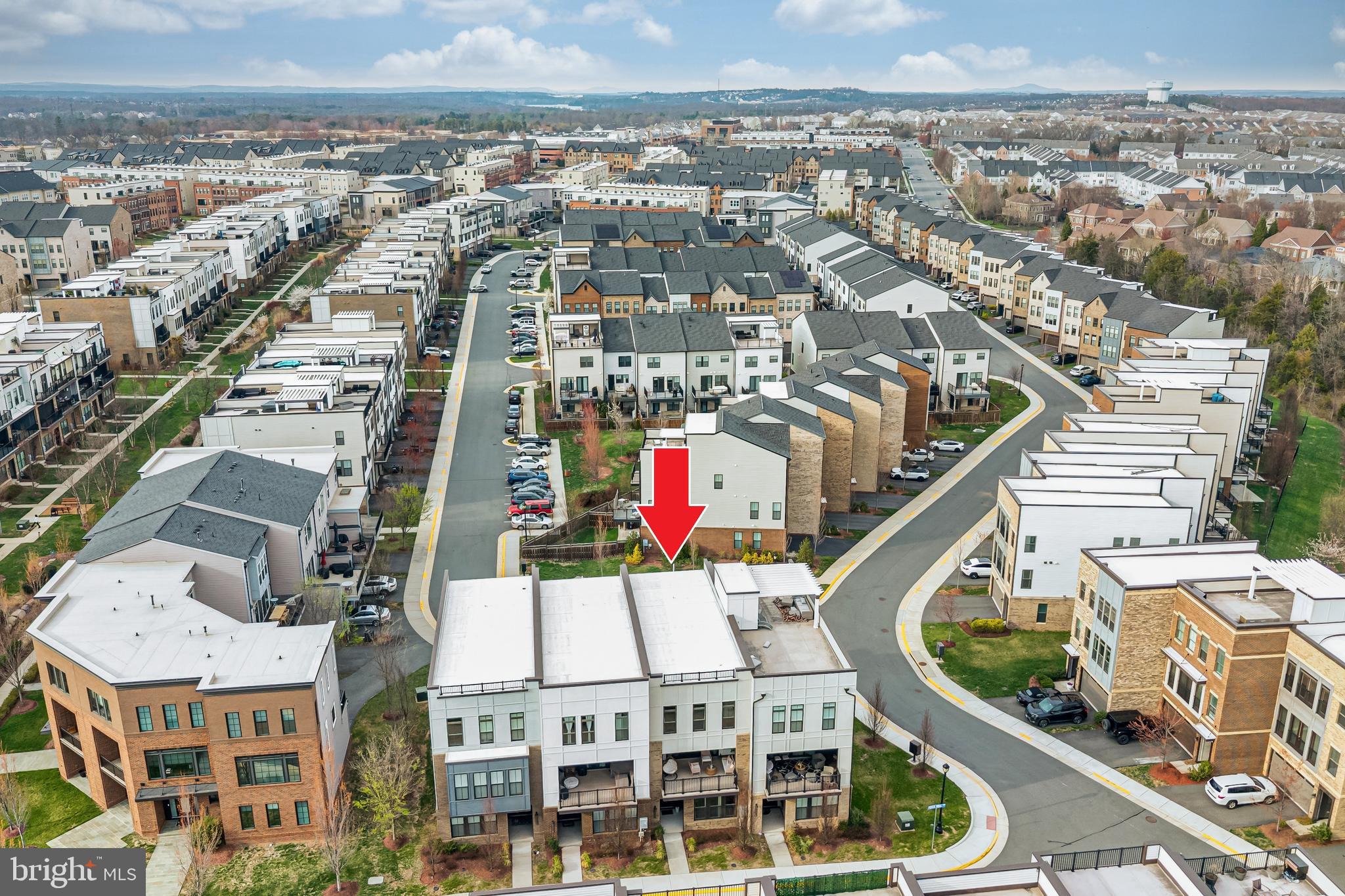 Welcome to this stunning contemporary Teagarden model by Van Metre Homes, A 4 bed room, 3.5 bath home offering nearly 2,850 sq ft of thoughtfully designed living space and over $100K in premium builder upgrades. This exceptional 3-level townhome stands out with rare structural enhancements, modern finishes, and a highly desirable, flexible layout designed for today’s lifestyle.The entry level features a true multi-generational suite complete with a full bath and spacious walk-in closet—perfect for guests, extended family, or a private retreat. This versatile space is pre-wired for a 7.1 home theater system and includes a wet bar rough-in, making it ideal for a recreation room, media lounge, or entertainment hub. Upgraded flooring and elegant oak stairs set the tone for the quality carried throughout the home.The main level is a game-changer, bright, open, and designed to impress. A chef-inspired gourmet kitchen anchors the space, featuring upgraded stainless-steel appliances, extended quartz countertops, premium soft-close cabinetry, and enhanced lighting. The seamless flow of upgraded hardwood flooring adds warmth and sophistication.What truly sets this home apart is the rare dual-deck design—one covered deck offering privacy and all-weather enjoyment with the option for automatic shutters, and a second open balcony with unobstructed neighborhood views With sliding glass doors on both sides, this level is flooded with natural light, creating an airy and inviting atmosphere.A dedicated main-level study provides a quiet and functional work-from-home space—an increasingly rare and valuable feature in townhome living. Custom drapes and upgraded lighting throughout further elevate the home’s modern elegance.Upstairs, the spacious primary suite offers a luxurious retreat with premium carpeting, an upgraded spa-like bathroom featuring designer tile, a frameless glass shower, rain head shower, dual vanity, and a generous walk-in closet with dedicated his-and-her space. Two additional well-sized bedrooms share a full bath, and a conveniently located upper-level laundry room with front-load washer and dryer adds everyday ease.The home is complete with a spacious rear-load two-car garage and ample guest parking right in front—another rare convenience.Ideally located within walking distance to Brambleton Town Center, this home offers unmatched access to dining, shopping, entertainment, the library, and Regal Cinemas. Enjoy nearby parks, scenic trails, playgrounds, and community amenities, all within minutes. Zoned for highly rated schools and just a short drive to major commuter routes and Dulles International Airport.This is a rare opportunity to own a highly upgraded, move-in ready home with premium features that are hard to find in today’s market. A perfect blend of space, style, and location—this home truly stands apart