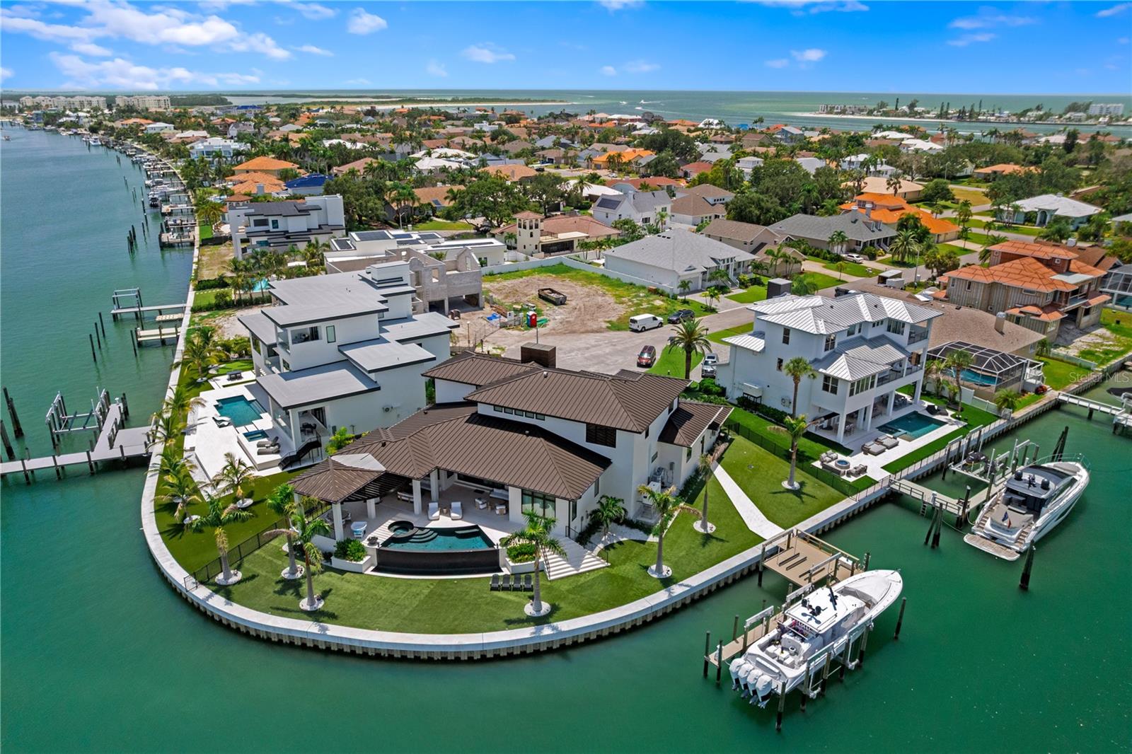 This custom luxury home, completed in 2023, exemplifies exceptional coastal living and architectural excellence, set on 200 feet of waterfront with seamless access to open Gulf waters - a true haven for boating enthusiasts.   • DESIGN: Created by the award-winning Sire Design team, known from Netflix’s Designing Miami and HGTV’s Divided by Design, the home was thoughtfully designed for indoor-outdoor flow, everyday comfort, and timeless appeal.   • SMARTLY BUILT: Elevated construction, impact-resistant windows, generator, supported by a pilings and stem wall foundation for enhanced structural integrity.   • LIVING SPACE: 5,251 square feet of air-conditioned space with 5 bedrooms, 6 full and 1 half bath, a loft, elevator, and two-2-car garages - all anchored by a dramatic 24-foot foyer with a custom pivot door.   • HOME AUTOMATION: A Savant system manages audio-visual, lighting, security, window treatments, televisions, and music - delivering seamless, effortless everyday living through a centralized platform.   • INTERIOR FINISHES: Oak Plank Flooring, Avocatus quartzite, Van Gogh onyx, walnut accents, CLE tile, Atelier de Troupe lighting, and Waterworks fixtures add warmth, character, and quality throughout.   • OUTDOOR LIVING: A negative-edge heated pool with spillover spa, covered lounge area, and artificial turf create a low-maintenance outdoor retreat perfect for relaxing or entertaining.   • DOCK & BOATING: A custom dock completed in 2022 includes a 40,000-pound lift for a 52-foot boat, 2 JetSki lifts, and a seawall completed in 2020. There is ample space to position a larger yacht as well.    • SETTING: Situated on a beautiful street in a peaceful waterfront setting, the home offers effortless access to the water, with the dock placed to the side to preserve open views. Located just minutes from beaches, parks, dining, shopping, and airports, this home offers a lifestyle defined by thoughtful design, premium finishes, and convenience - both on and off the water. Come experience the level of quality, comfort, and design that truly sets this home apart.