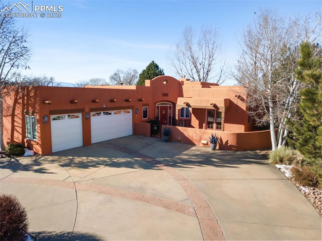Experience true Southwest elegance in this Adobe-style home located on the first hole of the Pueblo West Golf Course. A circular driveway, lush landscaping, and a serene fountain create a beautiful first impression. Inside, granite, detailed tile work, and solid wood cabinets set a luxurious tone. The foyer opens to a spacious living room featuring a Kiva-style fireplace that warms the living area, dining room, and outdoor patio. The formal dining room includes a wet bar and stunning views of the golf course, mountains, and the park-like backyard with concrete patios, both covered and open for entertaining. The gourmet kitchen offers granite countertops, stainless steel double ovens, gas cooktop, microwave, and refrigerator, highlighted by a suspended wood ceiling and recessed lighting. The primary suite features a two-way fireplace shared with a spa-like five-piece bath, complete with jetted tub and walk-in shower. Three additional spacious bedrooms share another five-piece bath. A convenient mudroom leads to the built-in hot tub—perfect for enjoying Colorado sunsets and mountain views. A stucco privacy wall surrounds the property, offering a peaceful, secluded setting. Schedule a showing today!