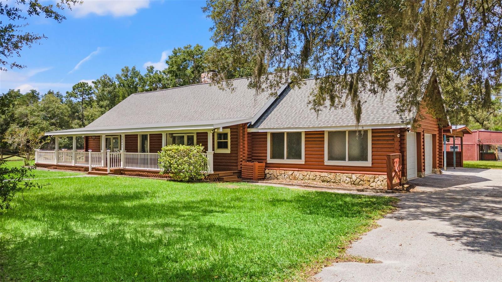 Welcome to Your Private Country EstateDiscover this magnificent 2,404 sq. ft. log ranch home with 3 bedrooms, 2.5 baths, attached 2-car garage, 2 stall carport, and a caged pool, all set on 5 fully fenced acres. Perfectly blending rustic charm with modern comfort, this property offers both seclusion and convenience.The acreage is thoughtfully designed with four separate gated paddocks, featuring both open pasture and shaded timber. An adjoining 2.5-acre rectangular parcel provides flexibility—use it for additional pasture, or sell it as an investment. At the end of a quiet, secluded road, this home offers true privacy—no neighbors in sight.Equestrian and hobby enthusiasts will appreciate the four-stall barn with electricity and its own well. Whether refurbished for horses or reimagined and rebuilt as a pole barn, workshop, or guest house, the possibilities are endless.Step inside to a warm and inviting lodge-style family room, centered around a dramatic 20-foot, floor-to-vaulted ceiling stone fireplace. The updated kitchen features stone countertops, a hooded island cooktop, and stainless steel appliances, including a 2023 smart touch-screen refrigerator and a built-in double oven.Every window offers a view—whether it’s the Spanish moss-draped oaks in the front yard, the peaceful fenced pasture, or the sparkling pool just outside the kitchen, master suite, and second bedroom.While this home feels like a private retreat, it’s only minutes from shopping, groceries, and the Suncoast Parkway—just 40 minutes to Tampa International Airport and 50 minutes to downtown Tampa. Only 1/2 mile to the paved 54 mile Suncoast Trail for biking and walking!No HOA. No flood zone.Recent updates include:2025: New garage doors, wraparound porch floorboards & stain, French doors, carpet in bedrooms2024: Pool pump2023: Double oven, refrigerator, AC unit2022: Roof2020: AC unitThis rare property offers the perfect canvas to create your own private country estate—complete with privacy, acreage, and the modern amenities of a rustic resort lodge.