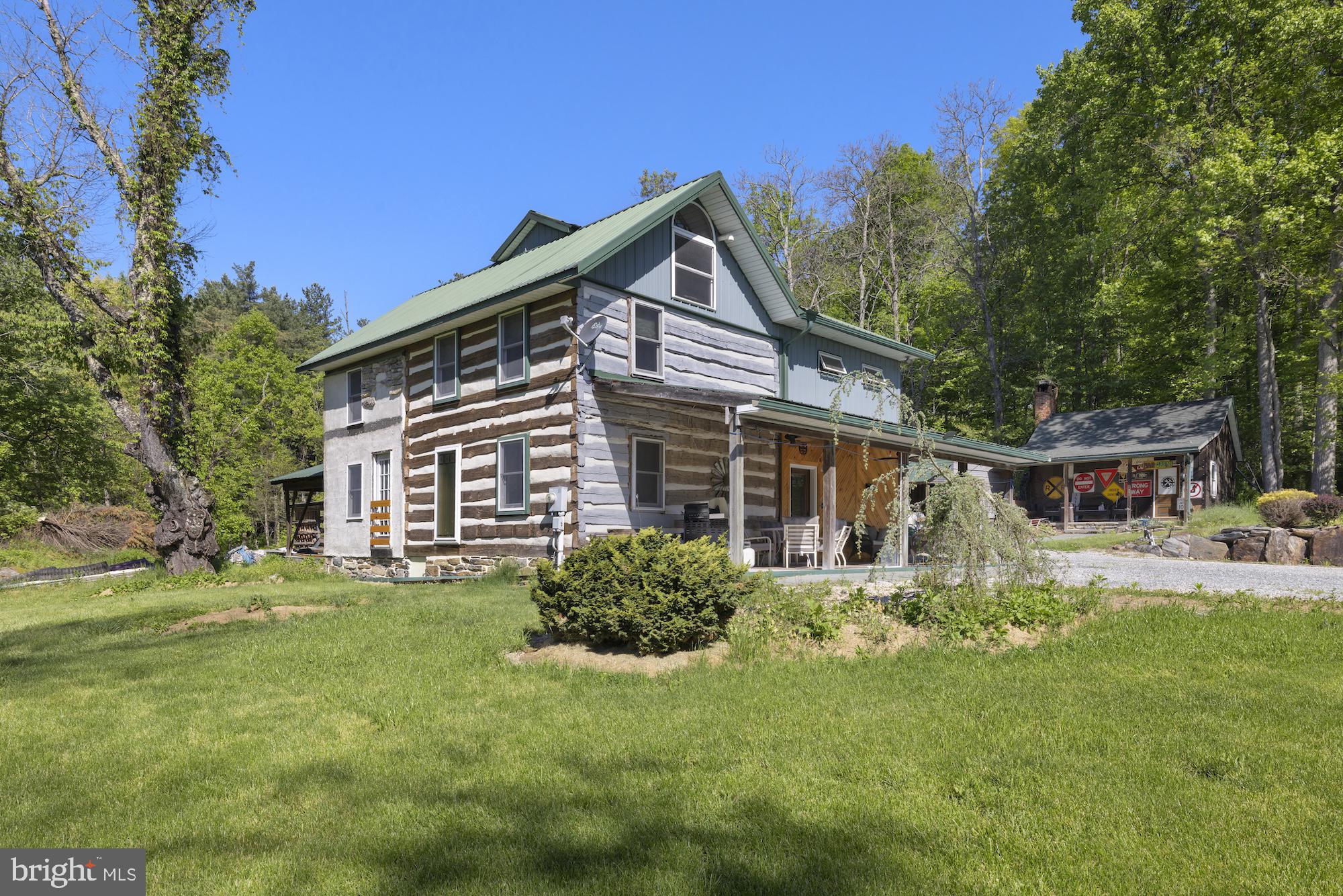 Situated on 20+ picturesque acres in Franklin Township, this unique property features an 1860 log home thoughtfully expanded with a 1999 addition, blending historic charm with modern comfort. Offering 3 bedrooms and 1 full bath with convenient main-floor laundry, the home is filled with character including exposed log walls, open beams, and an oversized kitchen designed for gathering and everyday living. A potential large primary bedroom provides additional flexibility for future expansion or customization.Comfort is enhanced with radiant heat, mini splits, and an outdoor wood furnace with dual-fuel oil backup for efficient year-round heating. Step through the sliding doors to a rear patio wired for a hot tub and large gazebo, perfect for relaxing and enjoying the peaceful surroundings. The covered front porch with ceiling fans create inviting outdoor spaces to unwind.The property also includes a 49x24 pole barn with electric and attached carport, ideal for storage, equipment, hobbies, or workshop use. An additional outbuilding offers excellent potential for a private office, studio, or remote-working space. With open acreage, privacy, and endless possibilities, this property is perfect for those seeking country living with room to expand.
