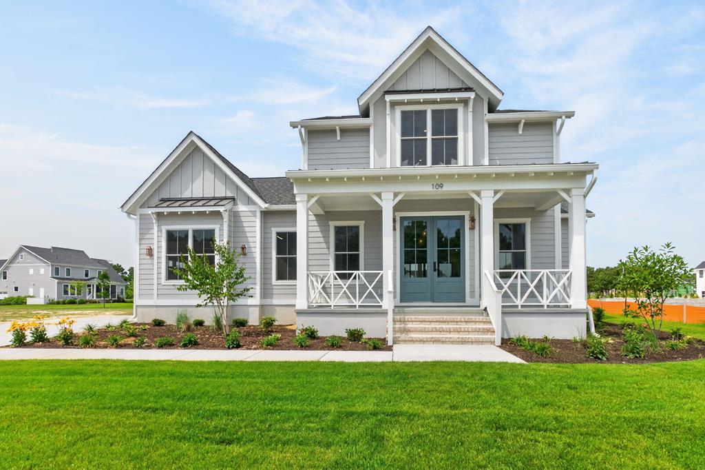 The Salt Meadow from Bay Creek Homes, constructed by Virginia Builders, blends coastal elegance and modern farmhouse design. The exterior features board and batten siding and metal roof accents. Inside, find a foyer with a shiplap ceiling and a family room with a brick fireplace. The gourmet kitchen boasts an island, white shaker cabinets, and a custom wood range hood, flowing into a dining area with wood beams and a shiplap ceiling. The main-level owner's suite offers a luxe bath and walk-in closet. Enjoy a large screened porch, a mudroom with a built-in bench, and a 2-car garage. Upstairs features a massive loft with a window nook, 2 bedrooms, and a full bath. Perfectly designed for luxurious, laid-back living!