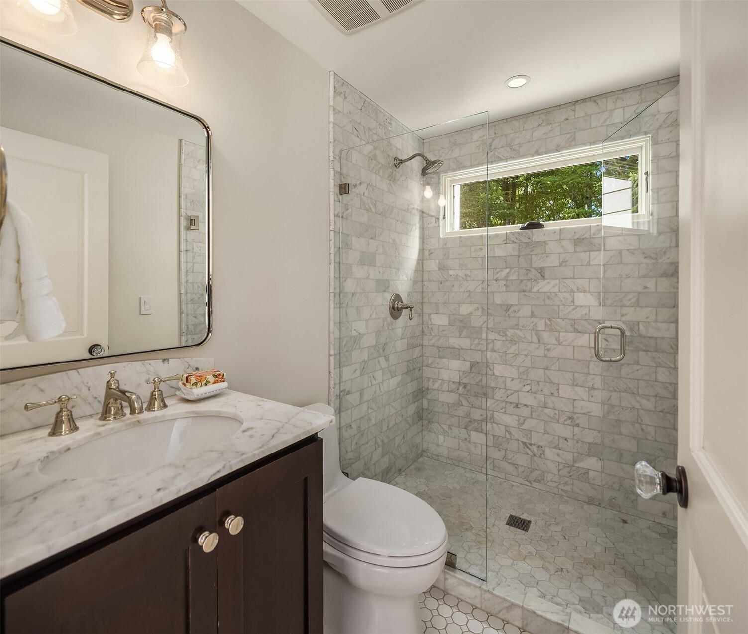 Guest bath finished with a glass shower and dark wood vanity