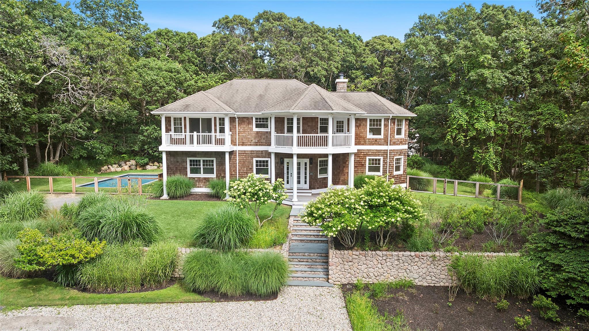 Nestled on a wooded 0.72 acre lot just moments from Hither Hills Beach (beach rights included), 26 Davis Drive in Montauk, NY is a coastal story waiting to unfold. Built in 2001 and beautifully transformed in its most recent renovation, this 4,200?sq?ft waterfront-inspired retreat now boasts four bedrooms and six baths (five full, one-half), marrying modern design with laid-back seaside living.
Imagine arriving at the polished cedar-shingled façade framed by mature landscaping, the air scented with salt breeze and garden blossoms. Step inside: an open-concept layout bathed in natural light reveals airy living spaces where wide-plank wood floors meet crisp white walls. The gourmet kitchen, anchored by a generous island and high-end appliances, flows effortlessly into family and dining areas—perfect for entertaining or quiet evenings alike.
A narrative of refinement continues upstairs where sumptuous primary and guest suites each feature luxe en-suite bathrooms and serene views over the property. Every bath reflects attention to detail, blending marble, custom cabinetry, and rich fixtures in flawless balance. The layout offers both privacy and shared spaces — ideal for families or friends gathering in style.
Outside, your private oasis awaits: a beautifully tiled gunite pool nestled in lush green surrounds, offering sunlit serenity by day and starry tranquility by night. A terrace just steps away from the house invites alfresco dining and lounge moments, whether hosting summer barbecues or reflecting under the moonlit sky.
Whether as a year round home or treasured seasonal retreat, 26 Davis Drive merges coastal elegance, modern comfort, and Montauk’s unique charm into one unforgettable address.