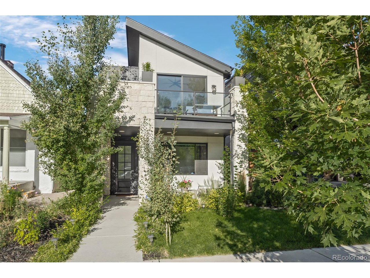 Tucked into one of Denver's most coveted neighborhoods, this home is a rare retreat that blends privacy, sophistication, and accessibility. Built in 2020, this 5-bedroom, 4-bathroom home spans more than 3,200 square feet of refined living space, offering both tranquility and the vibrancy of LoHi just beyond the front door. The main floor showcases an ideal layout with effortless flow between living, dining, and entertaining spaces. At its center, a chef's kitchen boasts an oversized quartz island, professional-grade appliances, and designer lighting. The living room, anchored by a sleek gas fireplace, opens through sliding glass doors to a lush backyard with mature trees, water feature, and stone patio -- perfect for quiet evenings or lively gatherings. A main-level bedroom or office with full bath provides flexibility. Upstairs, the primary suite is a private sanctuary, complete with vaulted ceilings, a sunlit terrace amongst the trees, and spa-inspired bath featuring dual vanities, soaking tub, and walk-in shower. A boutique-style custom closet elevates the retreat, while two additional bedrooms, a full bath, and laundry complete the upper level. The expansive rooftop deck redefines outdoor entertaining with a kitchenette, 6-burner gas grill, hot tub, and over 800 sq ft of space. Dine under custom shade sails, watch the city lights from the lounge and fire pit, or unwind in the hot tub with sweeping Denver skyline views. The finished basement extends the lifestyle experience with a theater, rec room, full bathroom, and bedroom -- currently curated as a fitness space. Detached two-car garage w/ the roof of the garage featuring a 6.2kW solar system that is fully owned and saves drastically on energy costs. Balancing serenity with city living, this Highlands residence is a lush, private oasis just minutes from Denver's acclaimed dining, shopping, and nightlife.